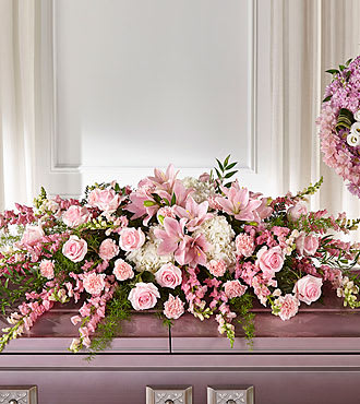 Pink floral arrangement with roses and lilies on a mantel