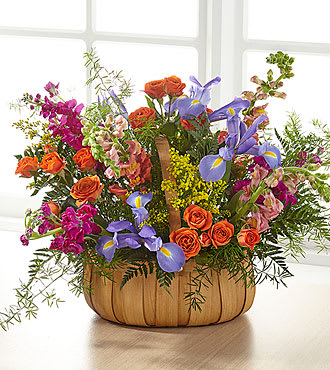 Mixed bouquet in a pumpkin-shaped container with orange, purple, and pink flowers