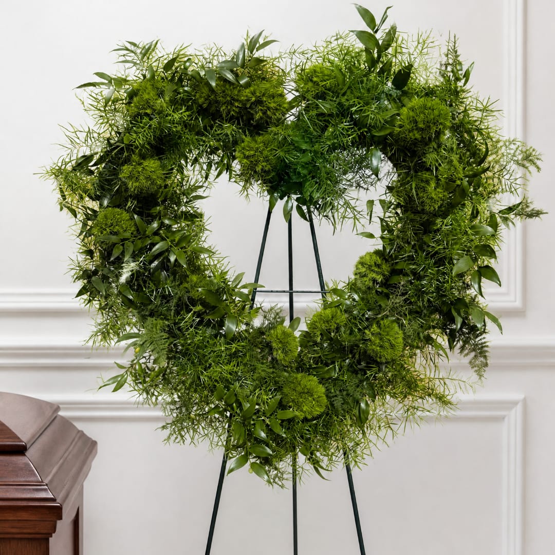 Green heart-shaped wreath on a black stand