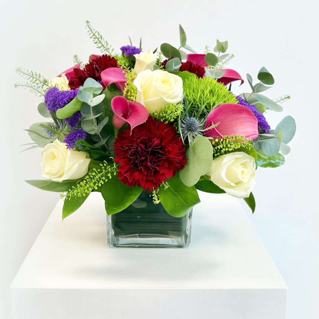 Mixed bouquet of roses, calla lilies, and carnations in a glass vase