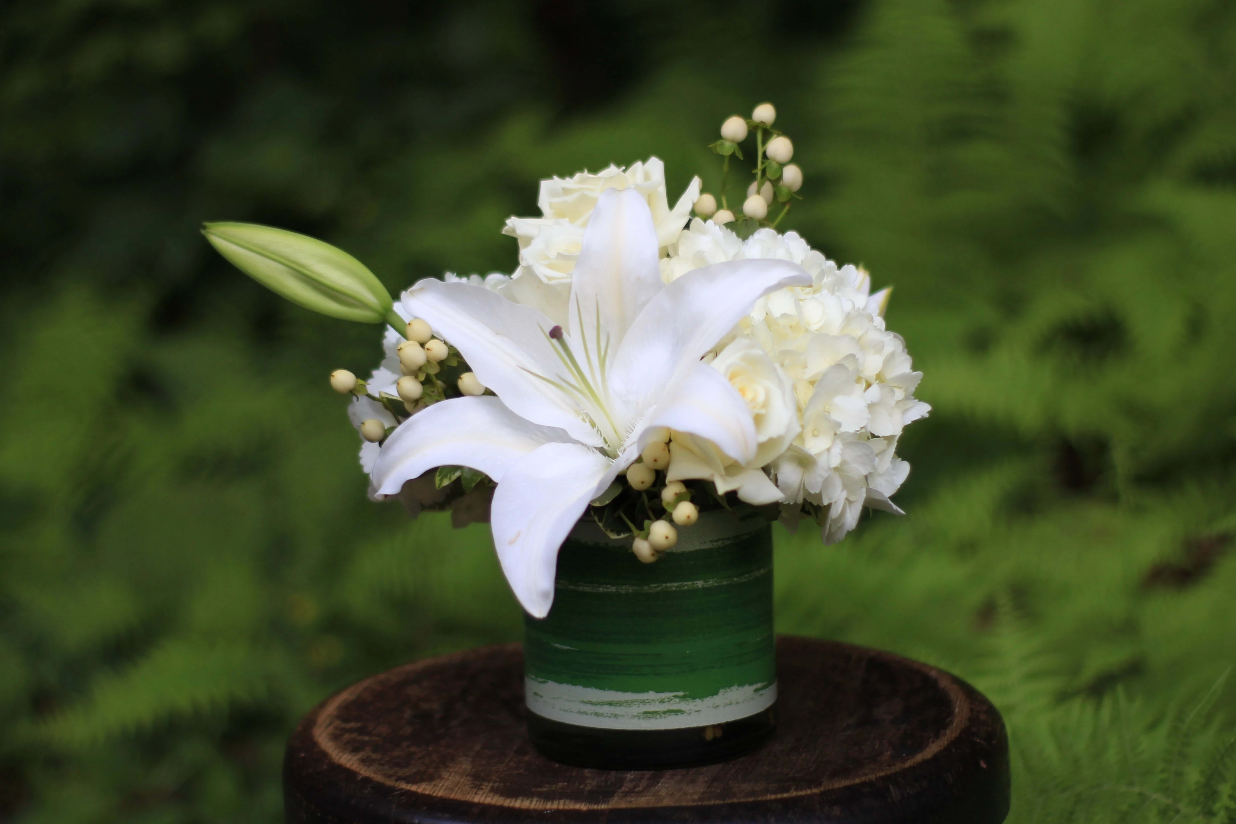 White lily and hydrangea arrangement in a green container