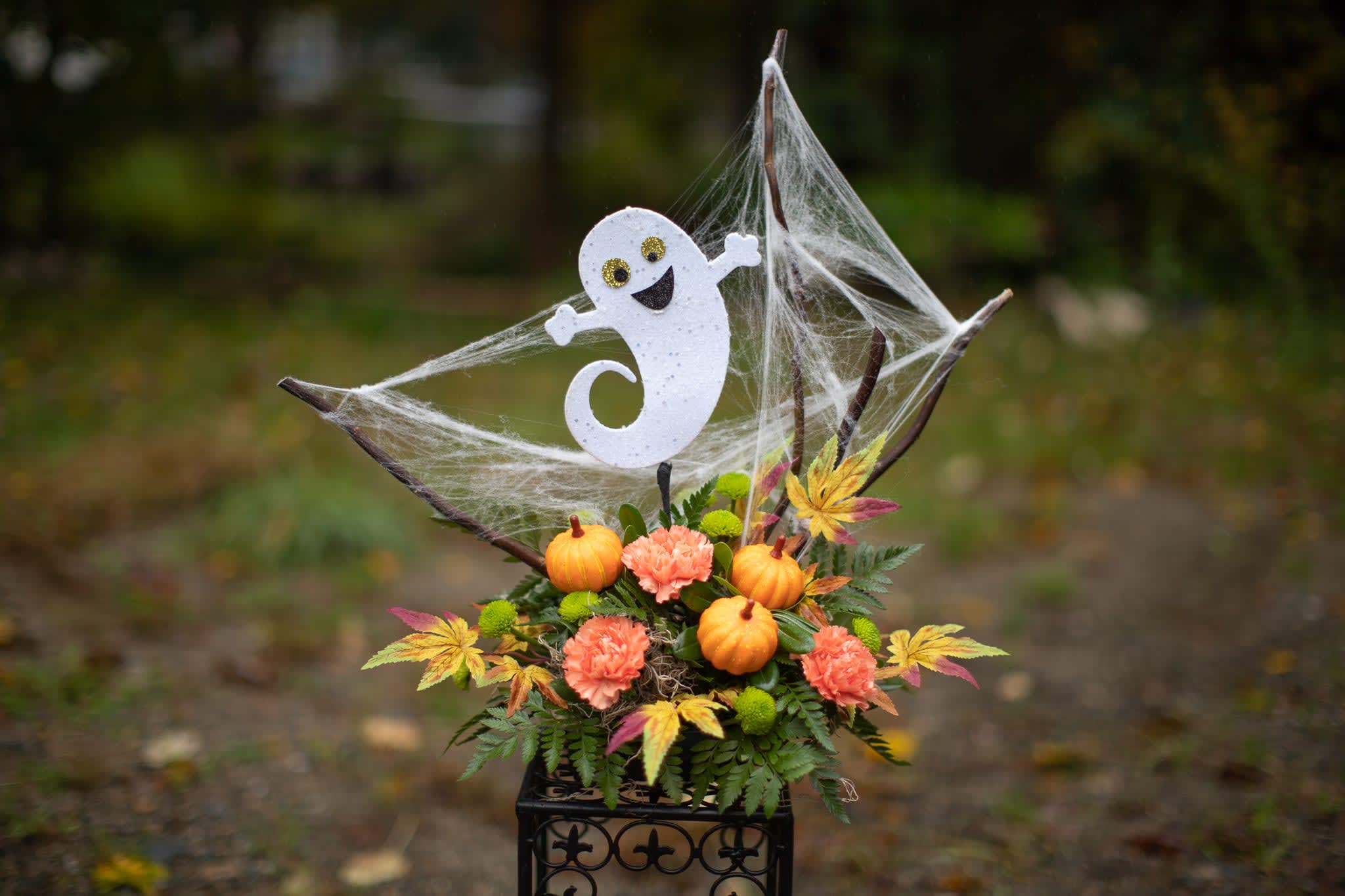 Halloween floral arrangement with pumpkins and a ghost topper