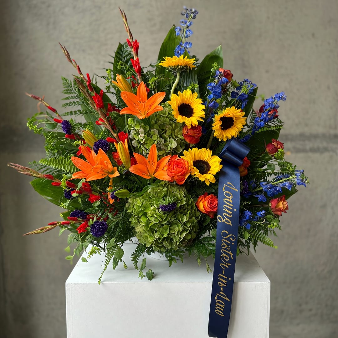 Colorful bouquet with sunflowers, orange lilies, and blue flowers in a vase