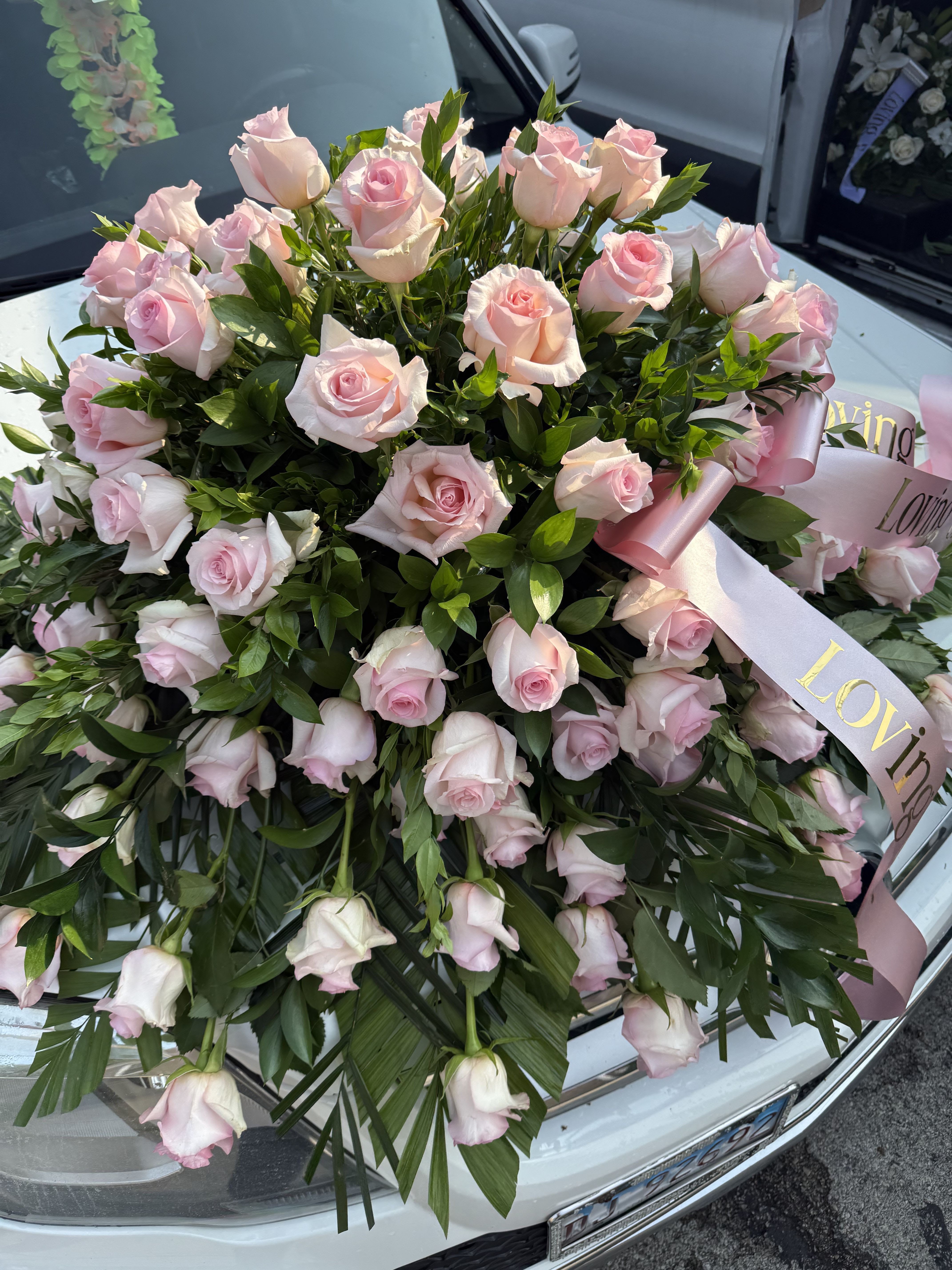 Large bouquet of pale pink roses with ribbon on a car hood