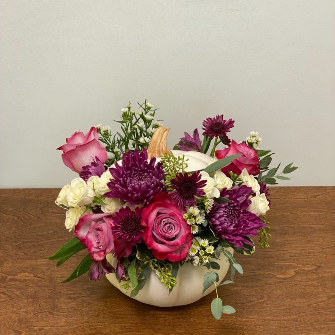 Pink and purple roses with white flowers in a white pumpkin vase