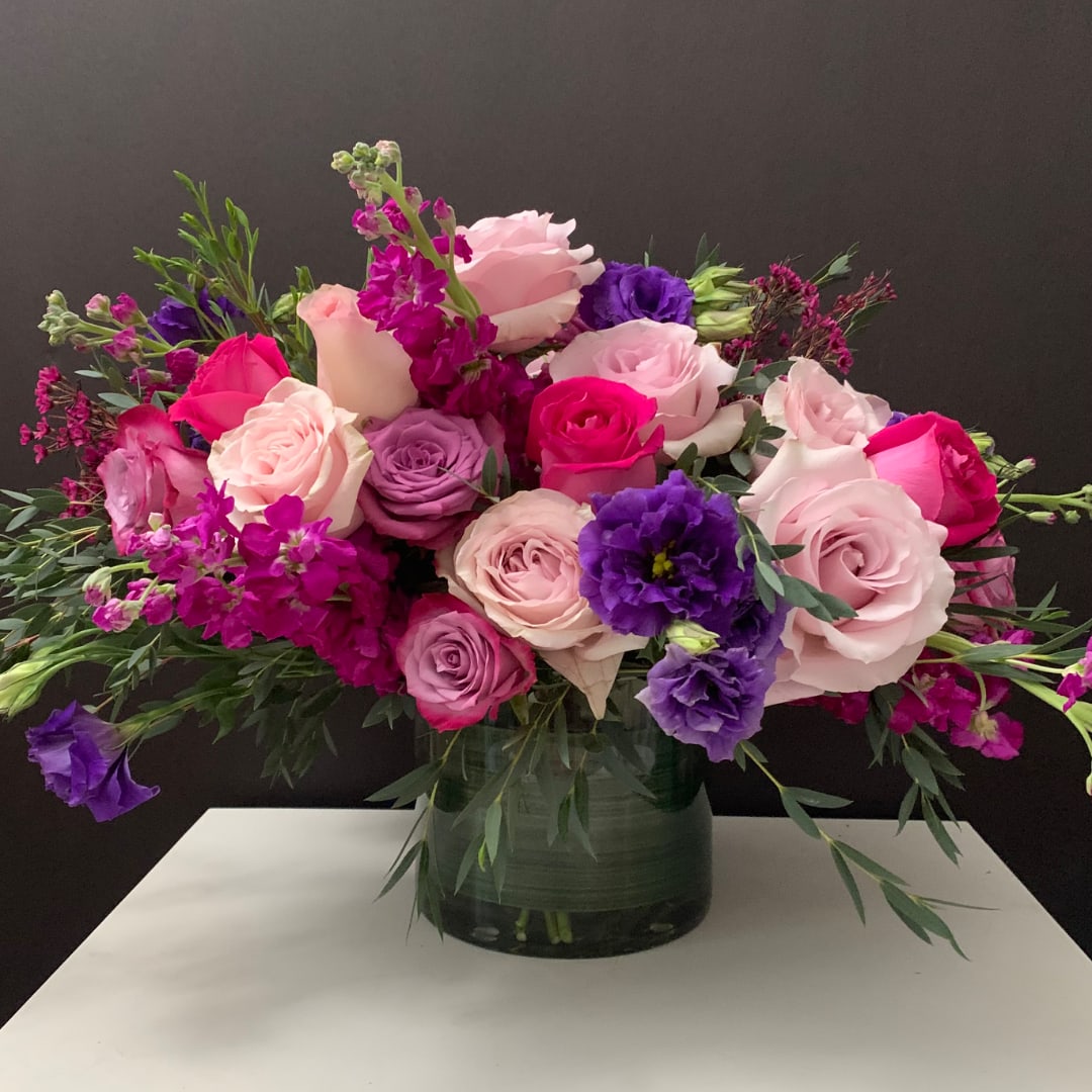 Bouquet of pink, purple, and white roses in a glass vase