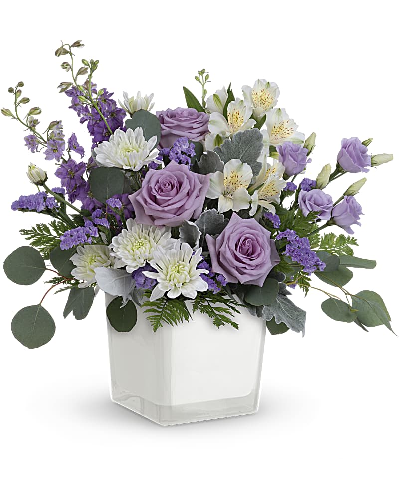 Lavender roses and white flowers in a clear square vase
