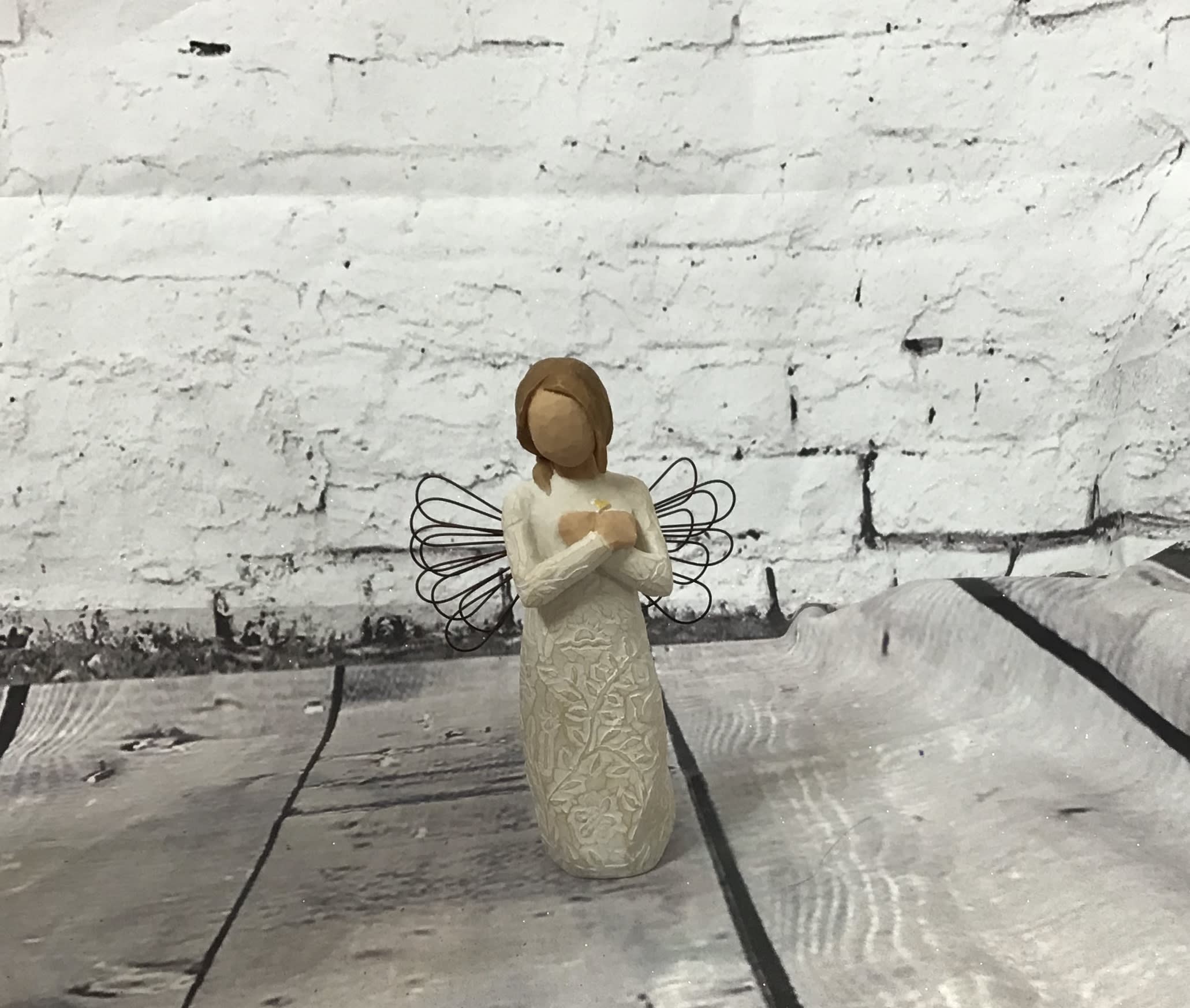 Small angel figurine with wire wings on a wooden surface