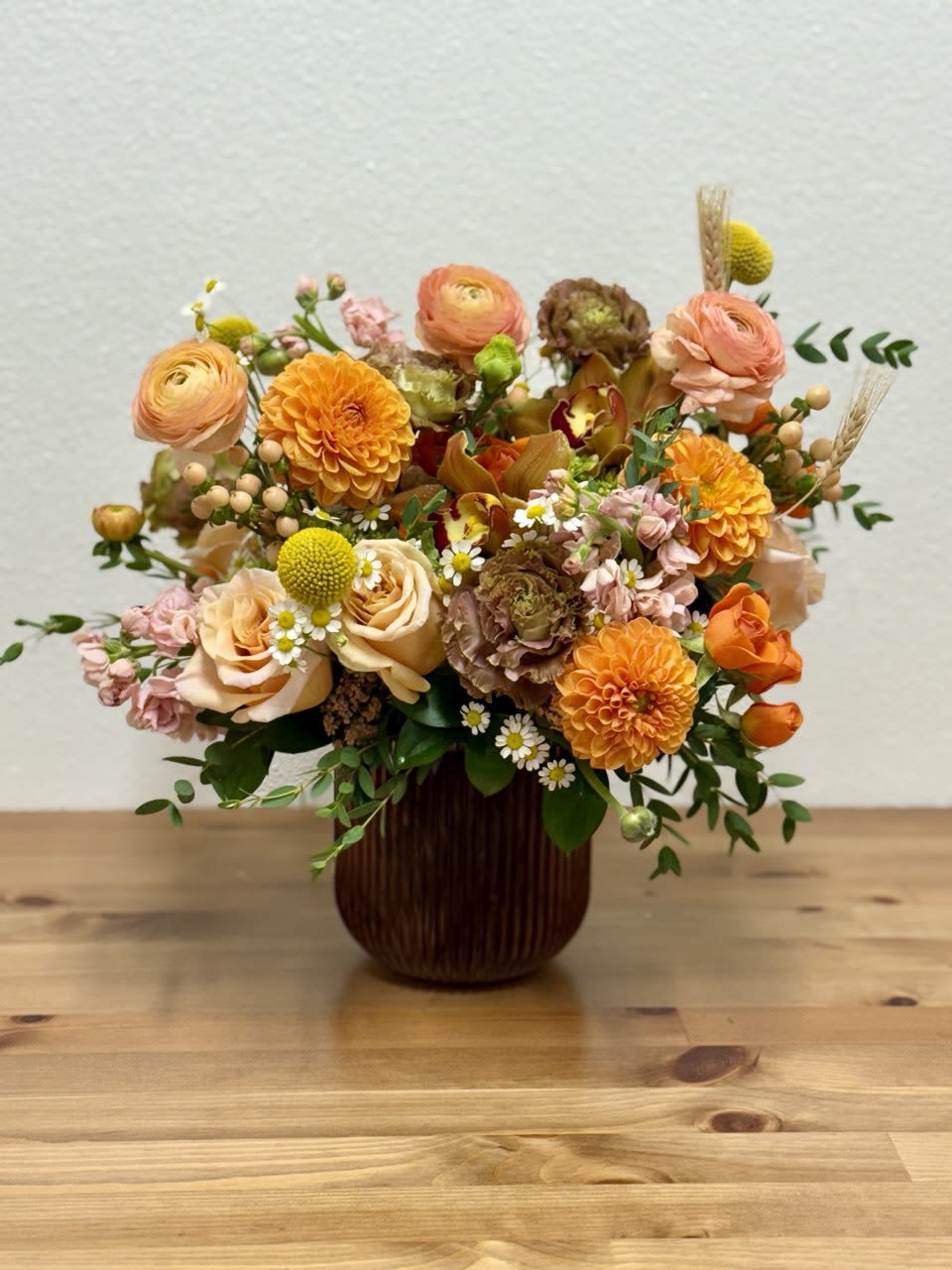 Mixed orange and peach flowers arranged in a dark vase