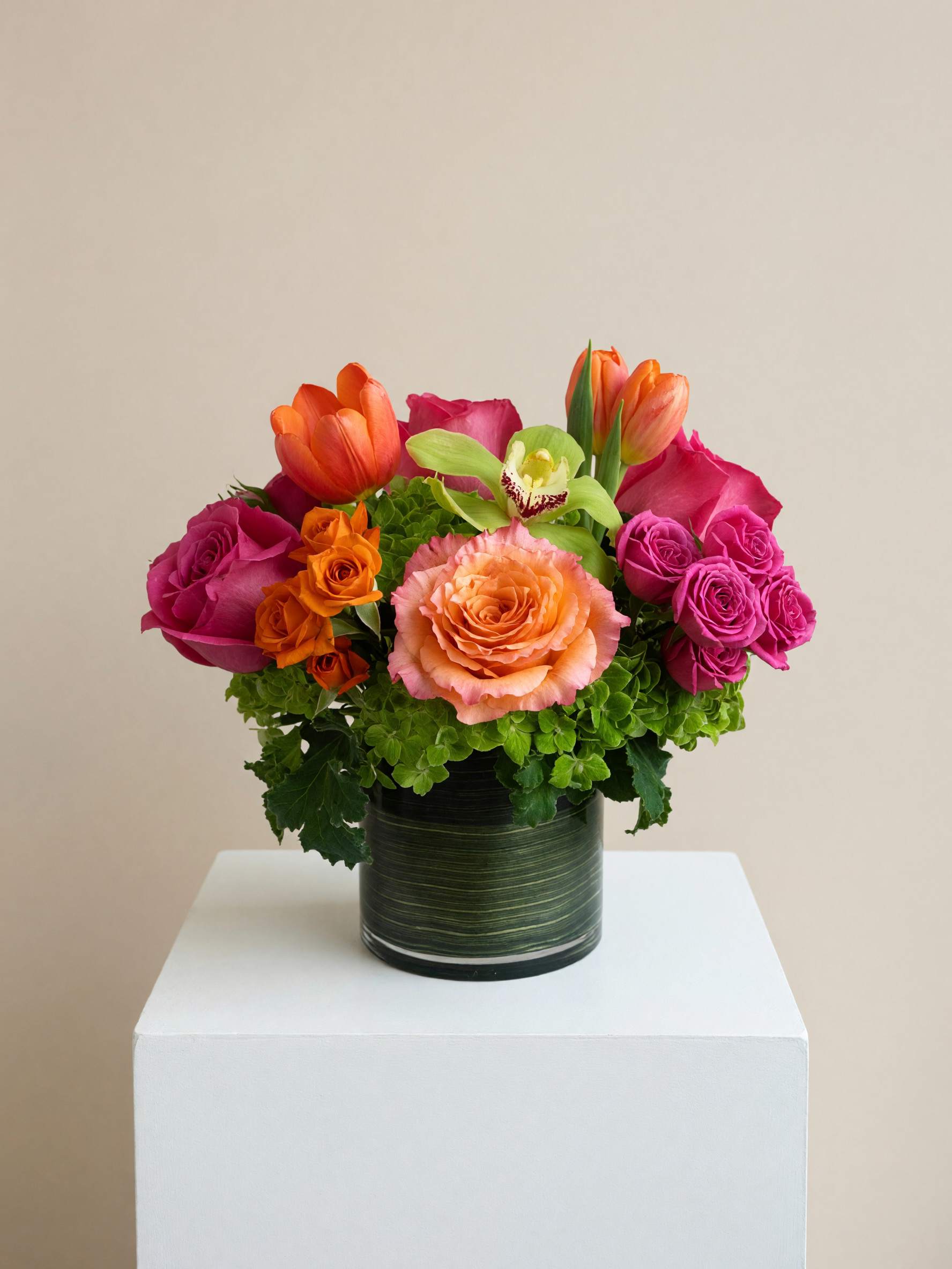 Colorful bouquet of roses and tulips in a dark green vase