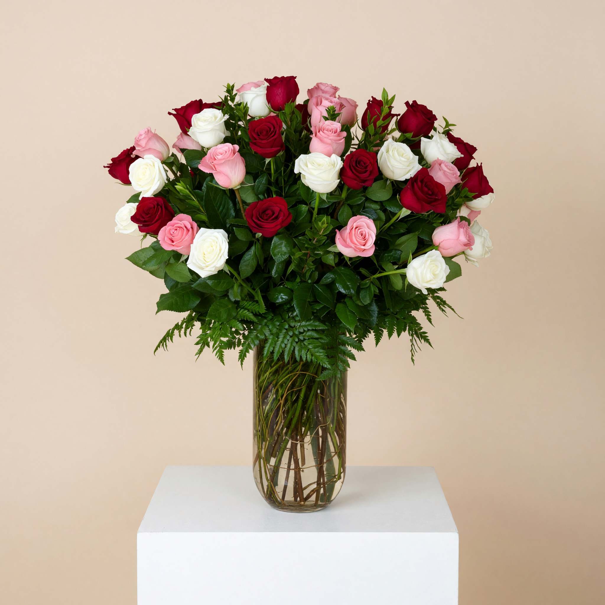 Bouquet of red, pink, and white roses in a clear glass vase