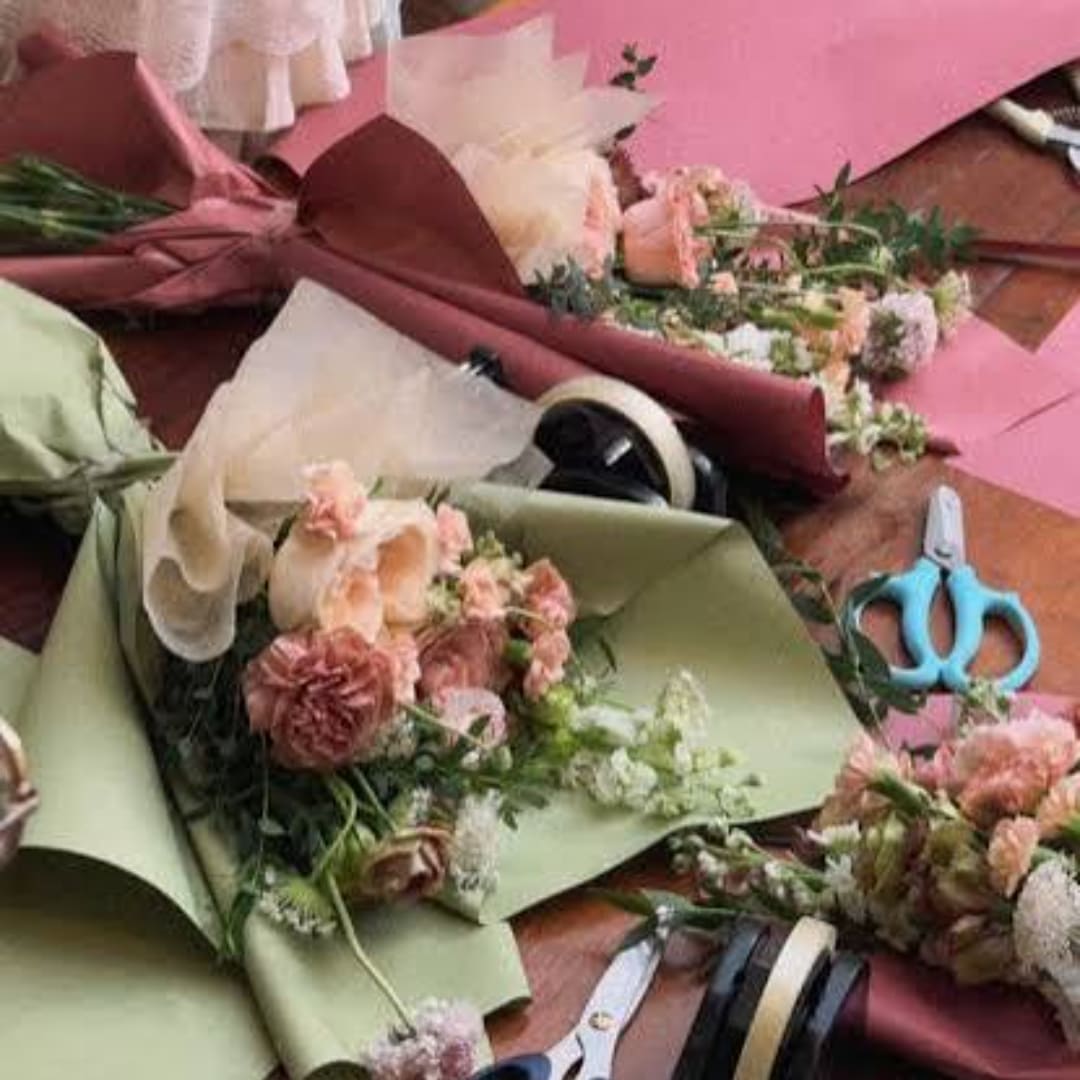 Bouquets of pink and cream flowers wrapped in colored paper on a table