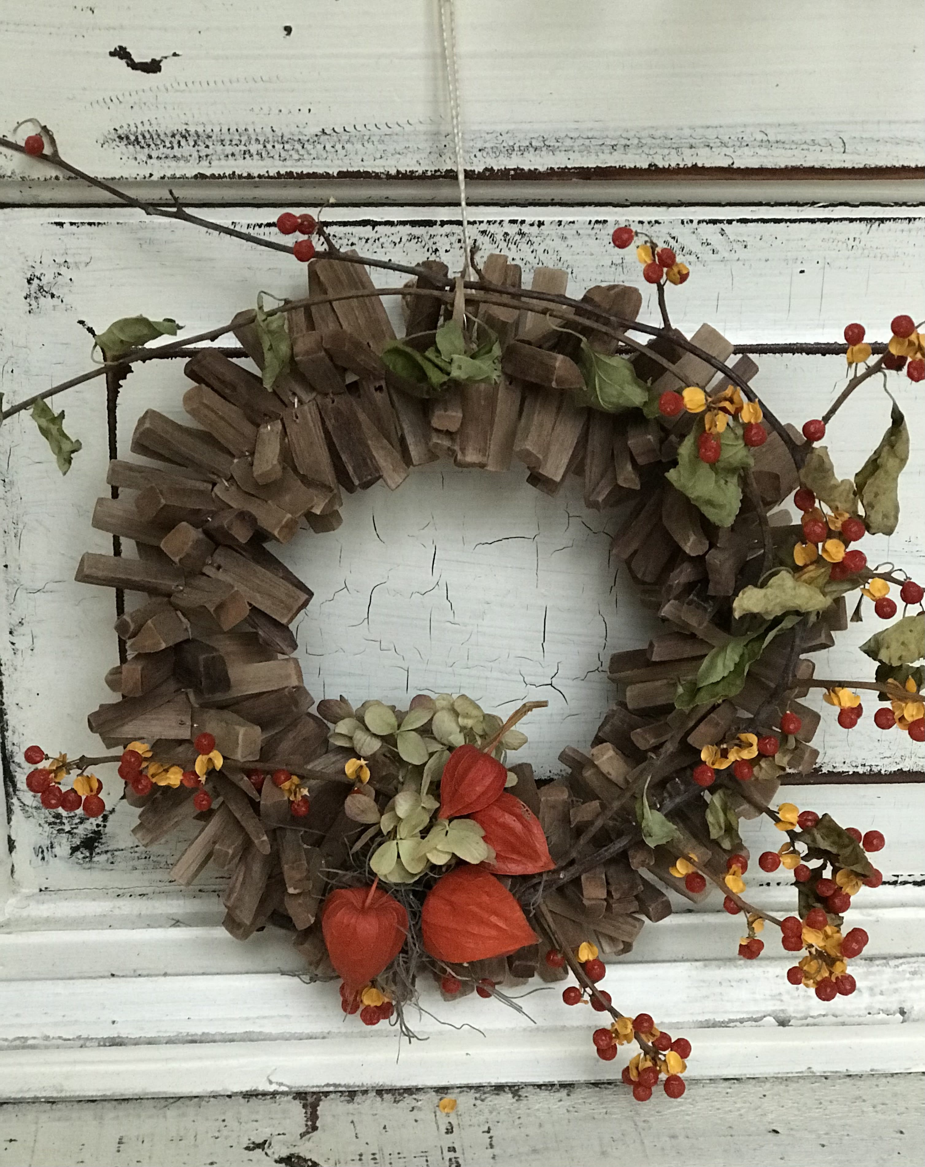 Autumn wreath with red berries and orange pods on a rustic wood ring