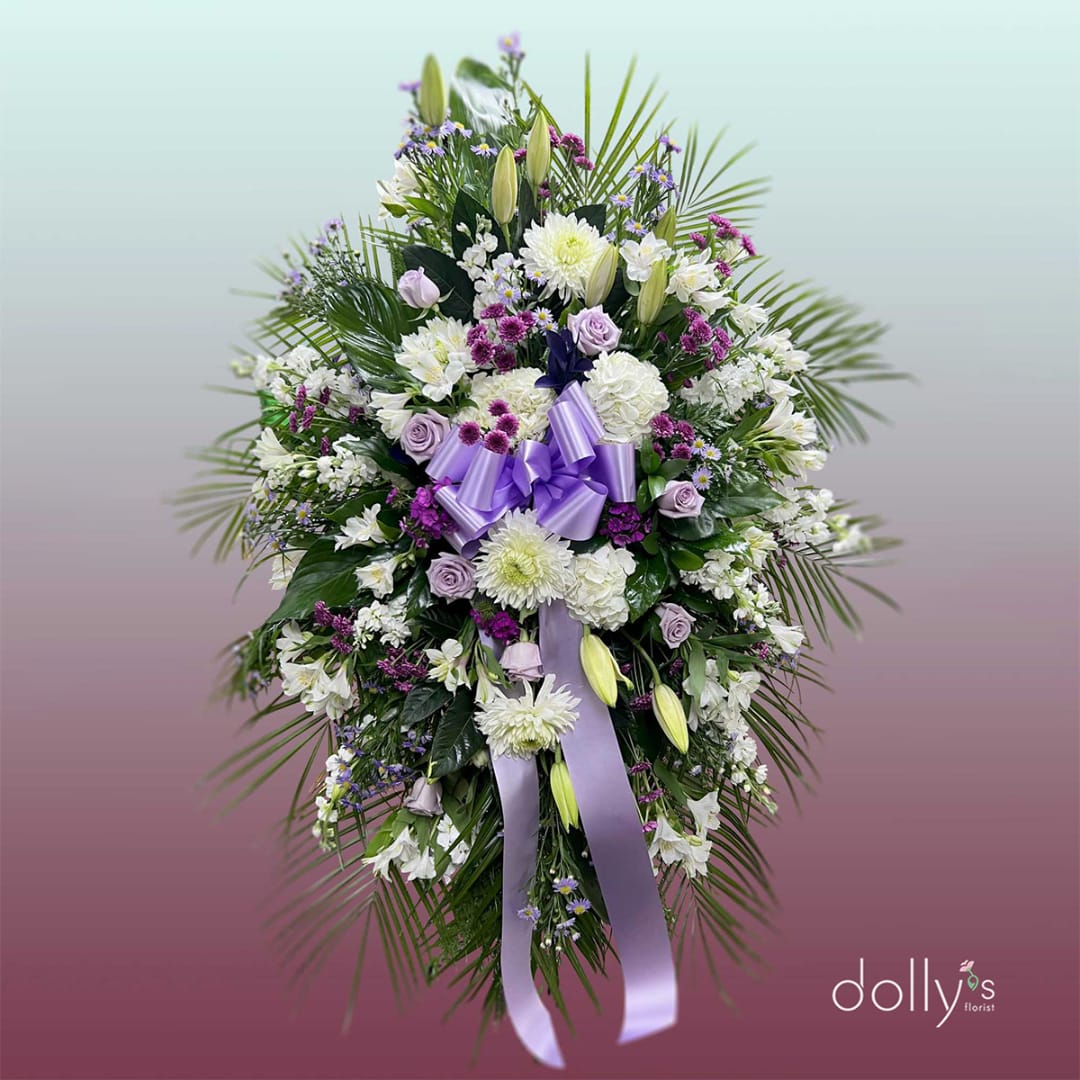 Standing floral spray with white and lavender flowers and a purple ribbon