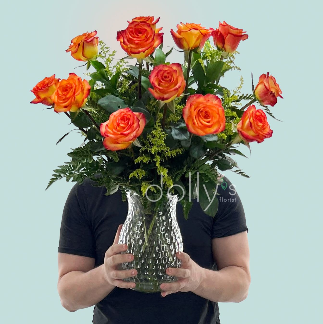 Classic Dozen High End Magic Long-Stem Roses - A radiant cluster of orange-and-yellow roses creates an immediate impression of warmth and joy-perfect as a love and romance surprise, anniversary gift, or a bright "just because" bouquet. This dozen long-stem arrangement reads as celebratory and sincere, the kind of floral gift that makes the person you're thinking of feel truly noticed on birthdays, graduations, or when you want to say thank you or I'm sorry.  The rounded, upright design is made up of lush orange-and-yellow roses with bright green filler for texture and contrast, presented in a deep purple glass vase that grounds the vivid palette with a bold, saturated base. The arrangement has a full, substantial presence and is sized as a medium-to-large vase design, delivering strong visual impact without overwhelming a room.  Send this when you want to lift spirits-an ideal pick-me-up for get well wishes or a joyful congrats moment-and know it arrives ready to display. For best longevity, keep the vase topped with fresh water and out of direct heat; simple daily care will keep these high-end roses looking fresh through the week.