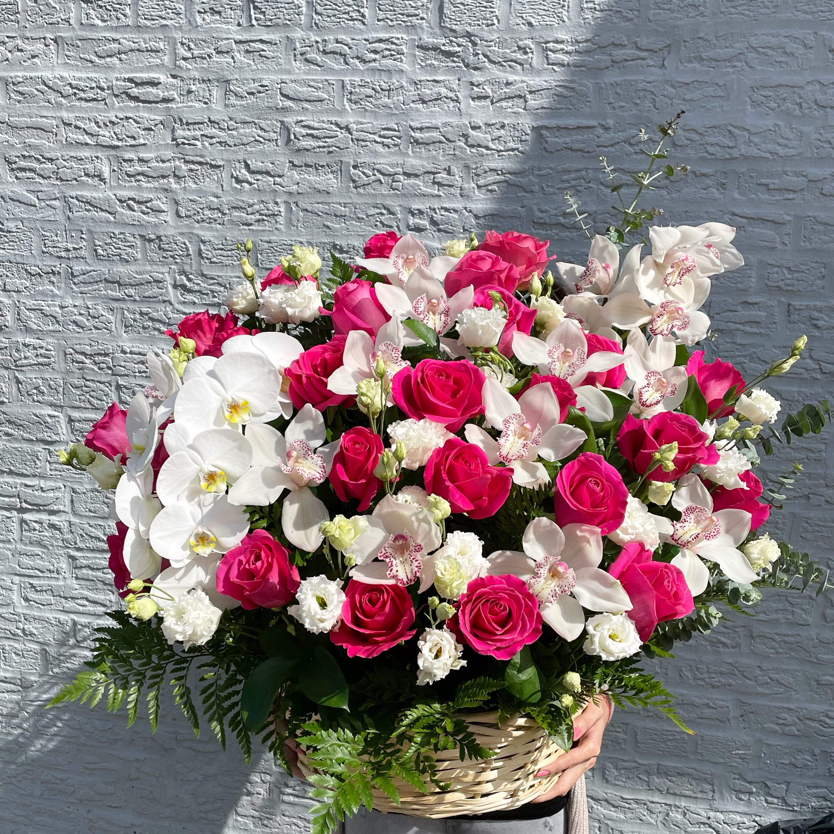 Basket arrangement of pink roses and white orchids