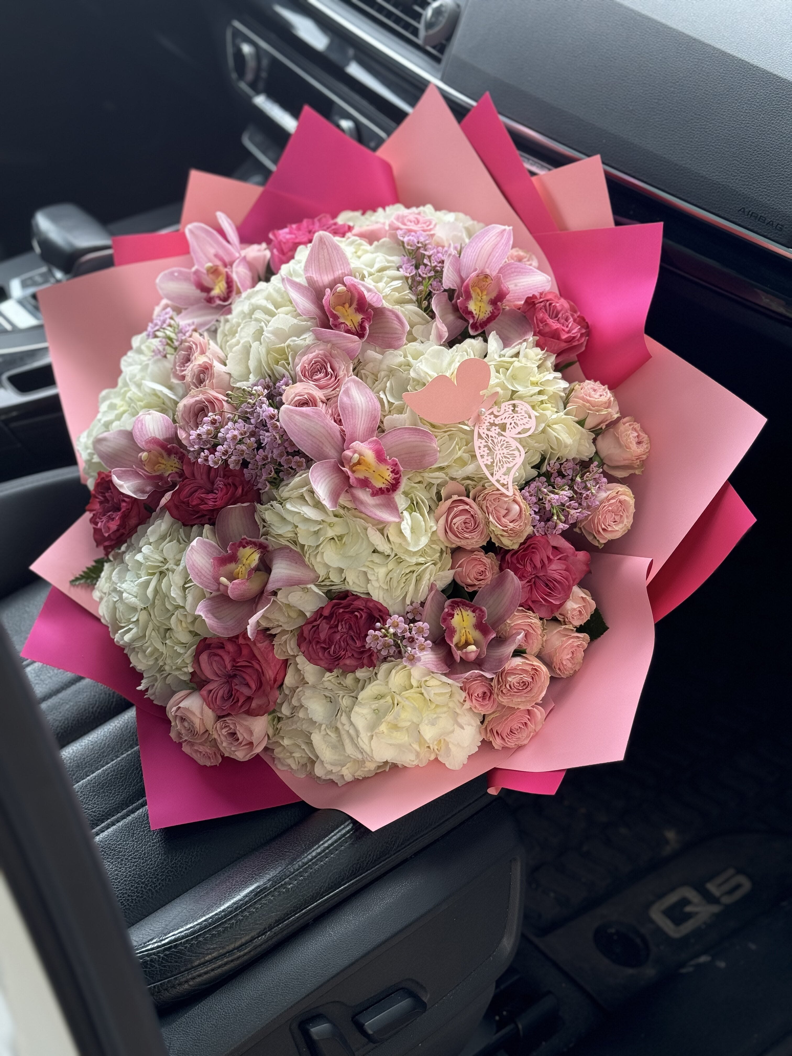 Pink and white bouquet with orchids and roses wrapped in pink paper