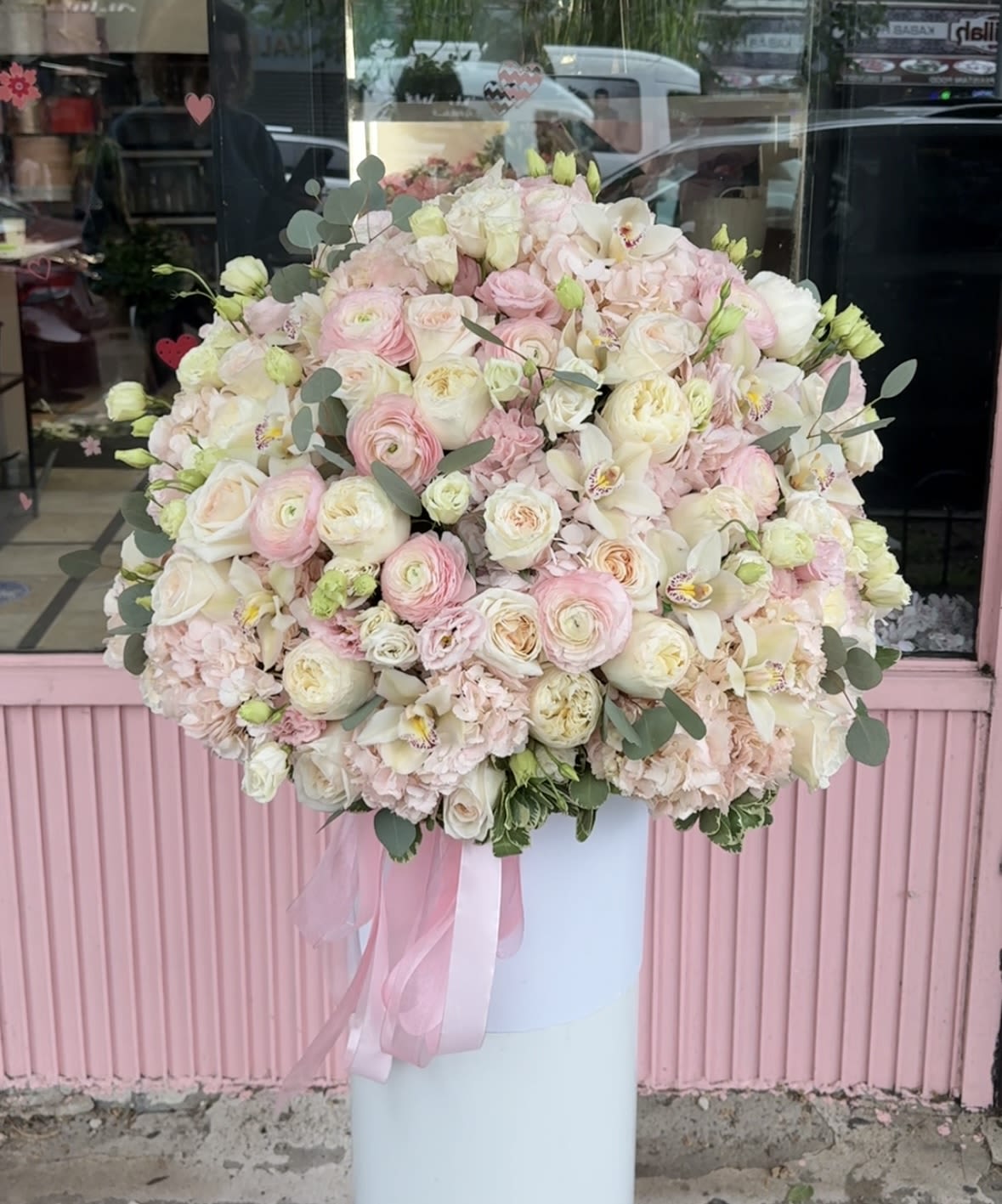 Large pastel bouquet of pink and white flowers in a tall white pedestal vase