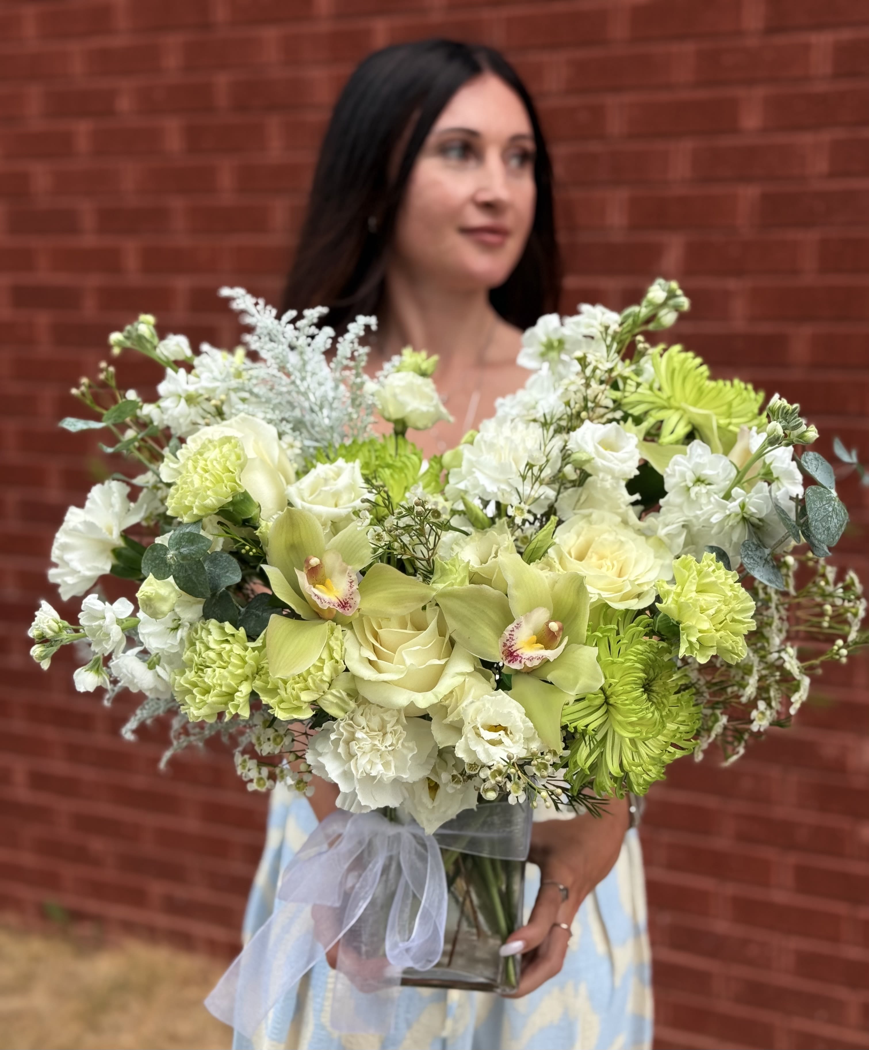 Large bouquet of pale green and white flowers in a glass vase