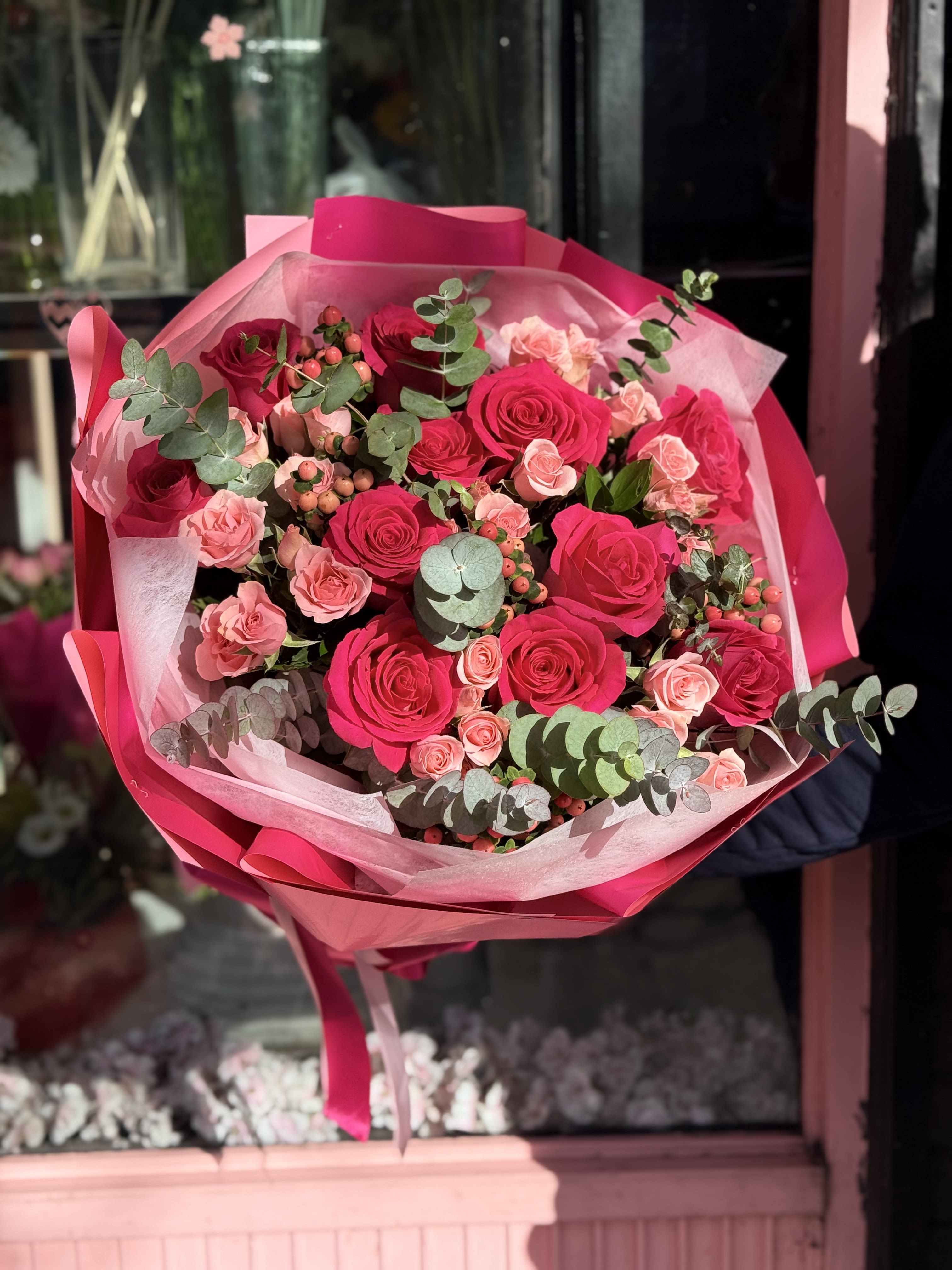 Bouquet of hot pink and blush roses wrapped in pink paper