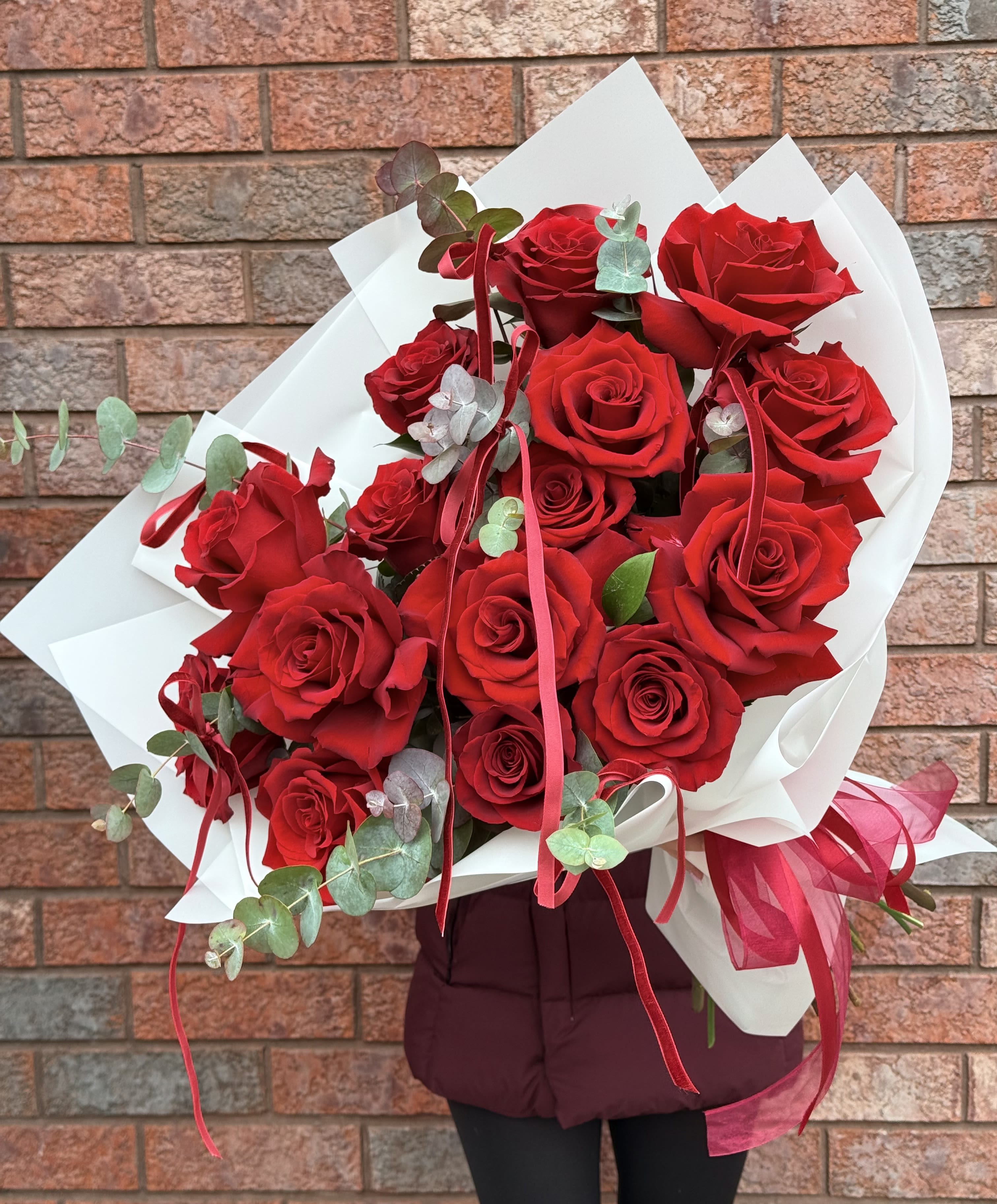 Bouquet of red roses wrapped in white paper with ribbon