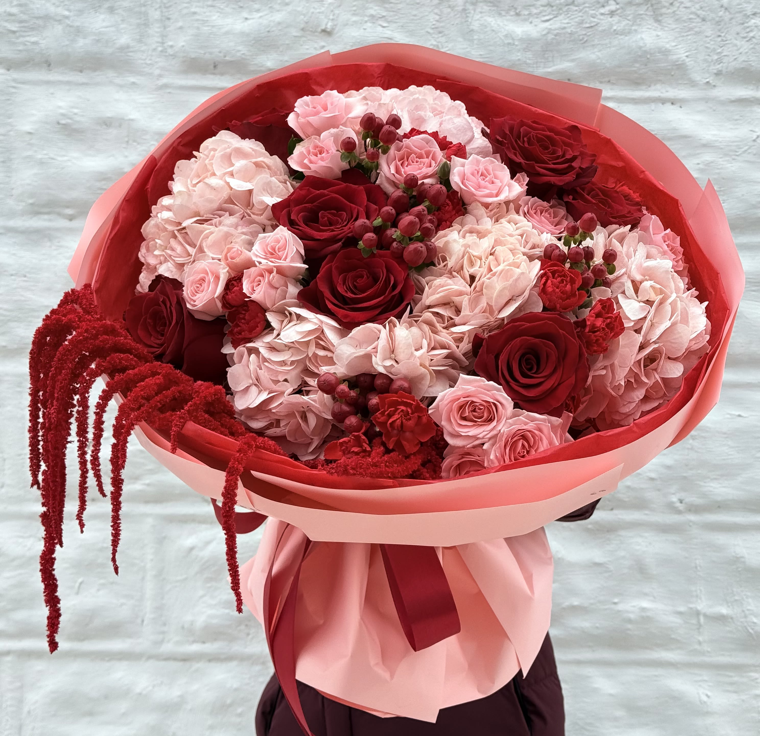 Bouquet of red and pink roses with hydrangeas wrapped in pink paper