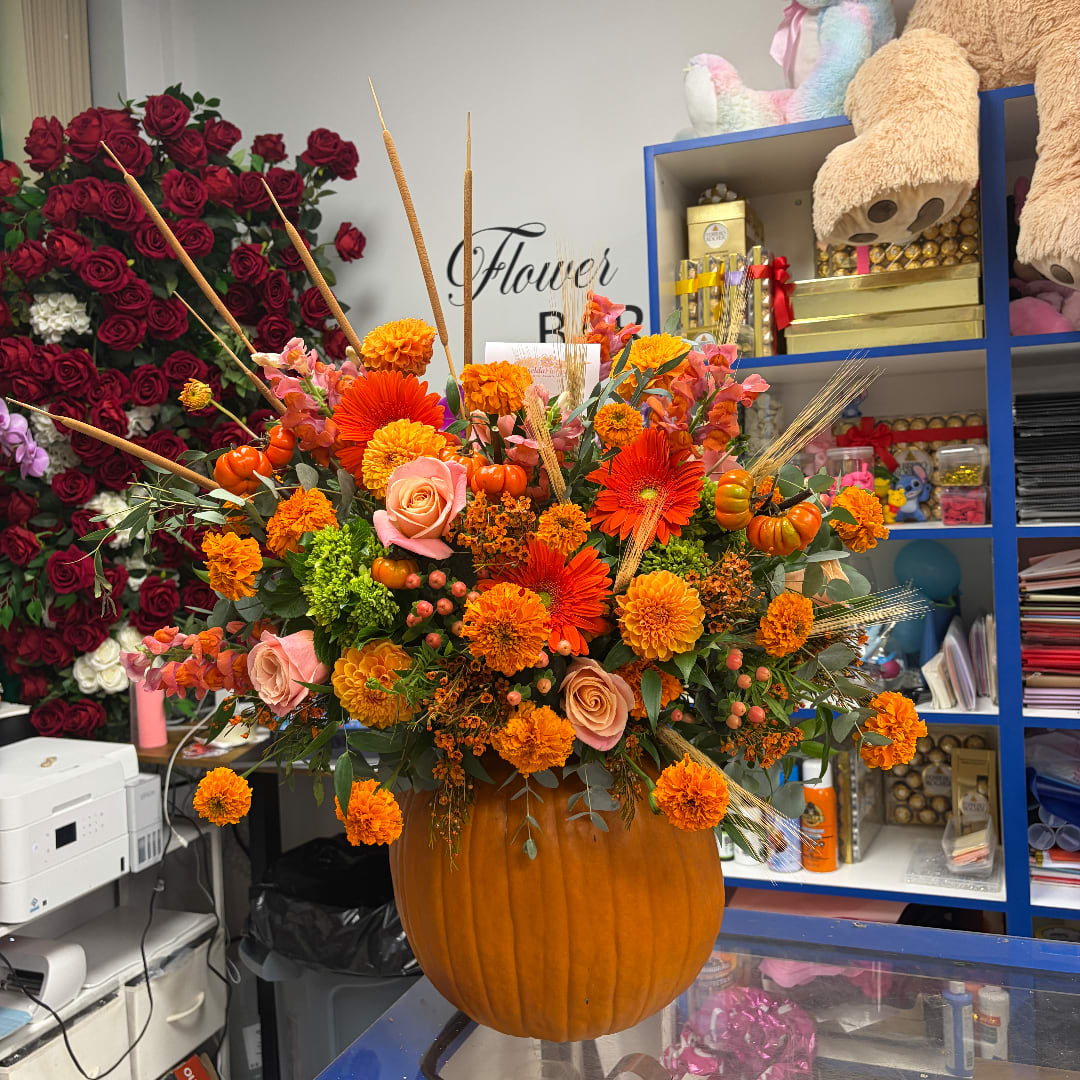 Autumn floral arrangement in a pumpkin container with orange and pink blooms