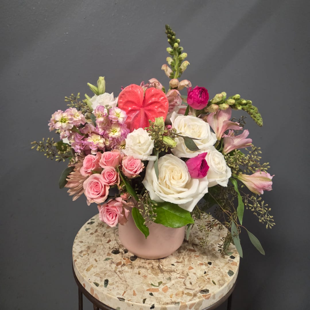 Pink and white rose arrangement in a blush vase with mixed blooms