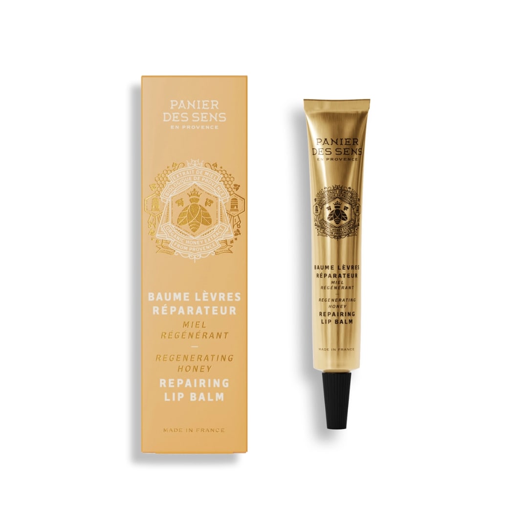 Gold lip balm tube beside matching box on a white background