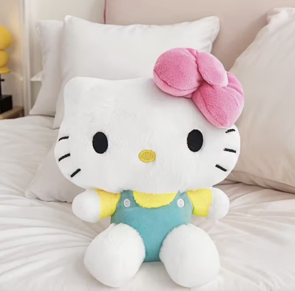Hello Kitty plush toy sitting on a bed with a pink bow
