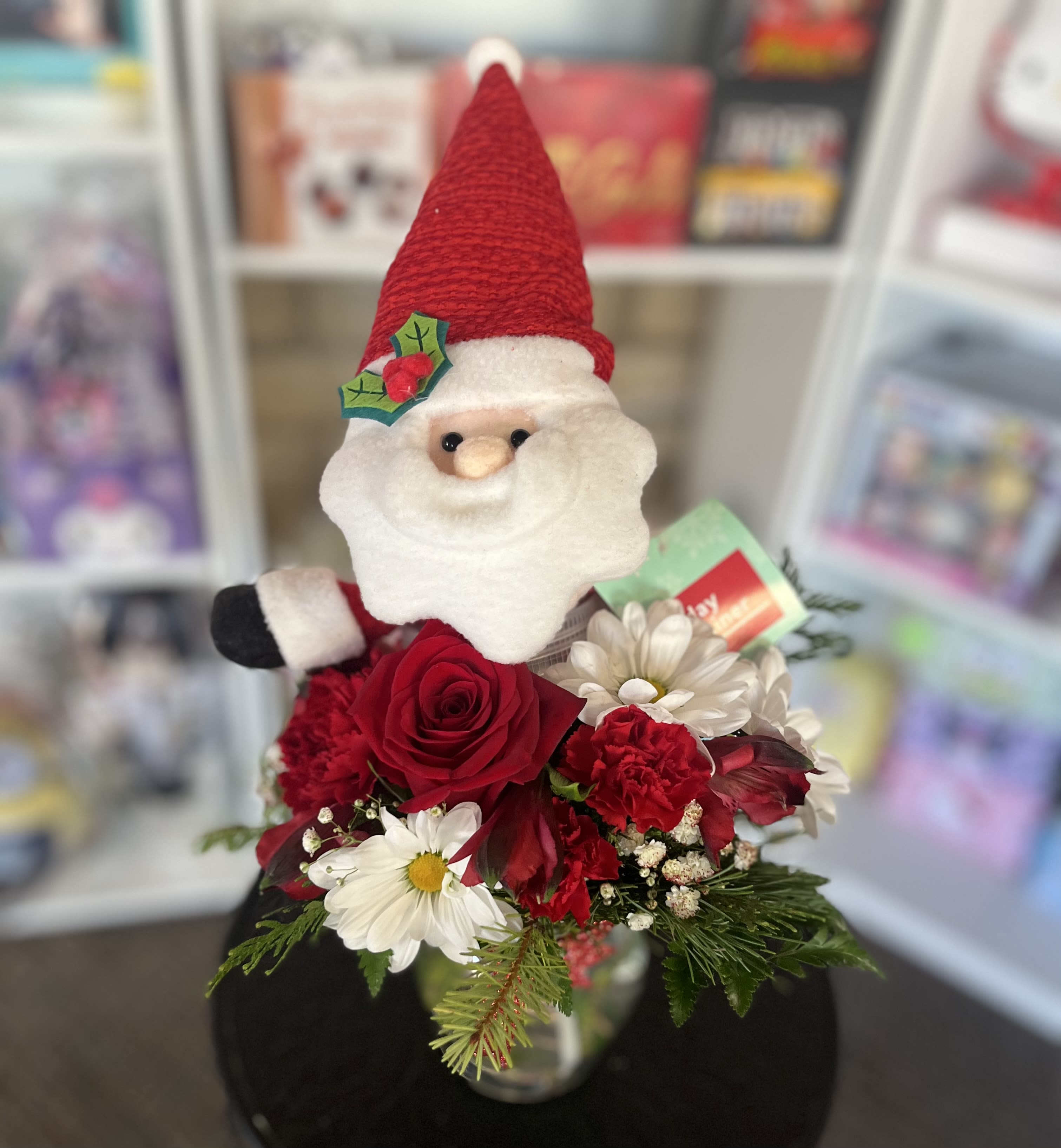 Santa figurine with red and white flowers in a vase
