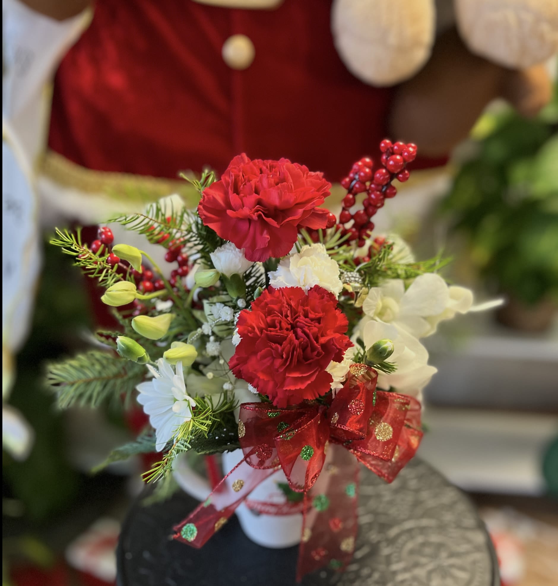 Red and white floral arrangement with a red ribbon in a white vase