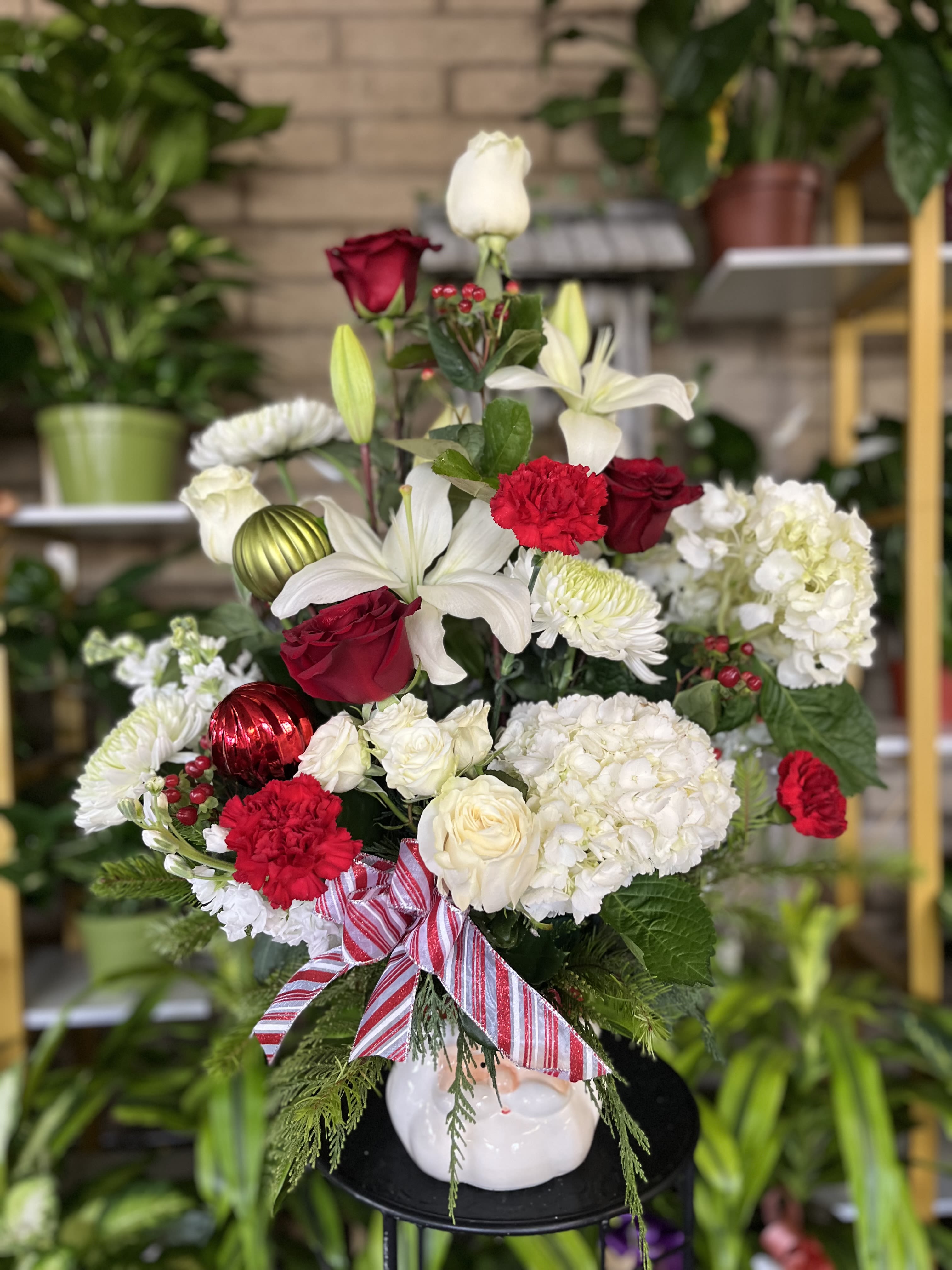 Red and white floral arrangement in a white vase with a striped ribbon