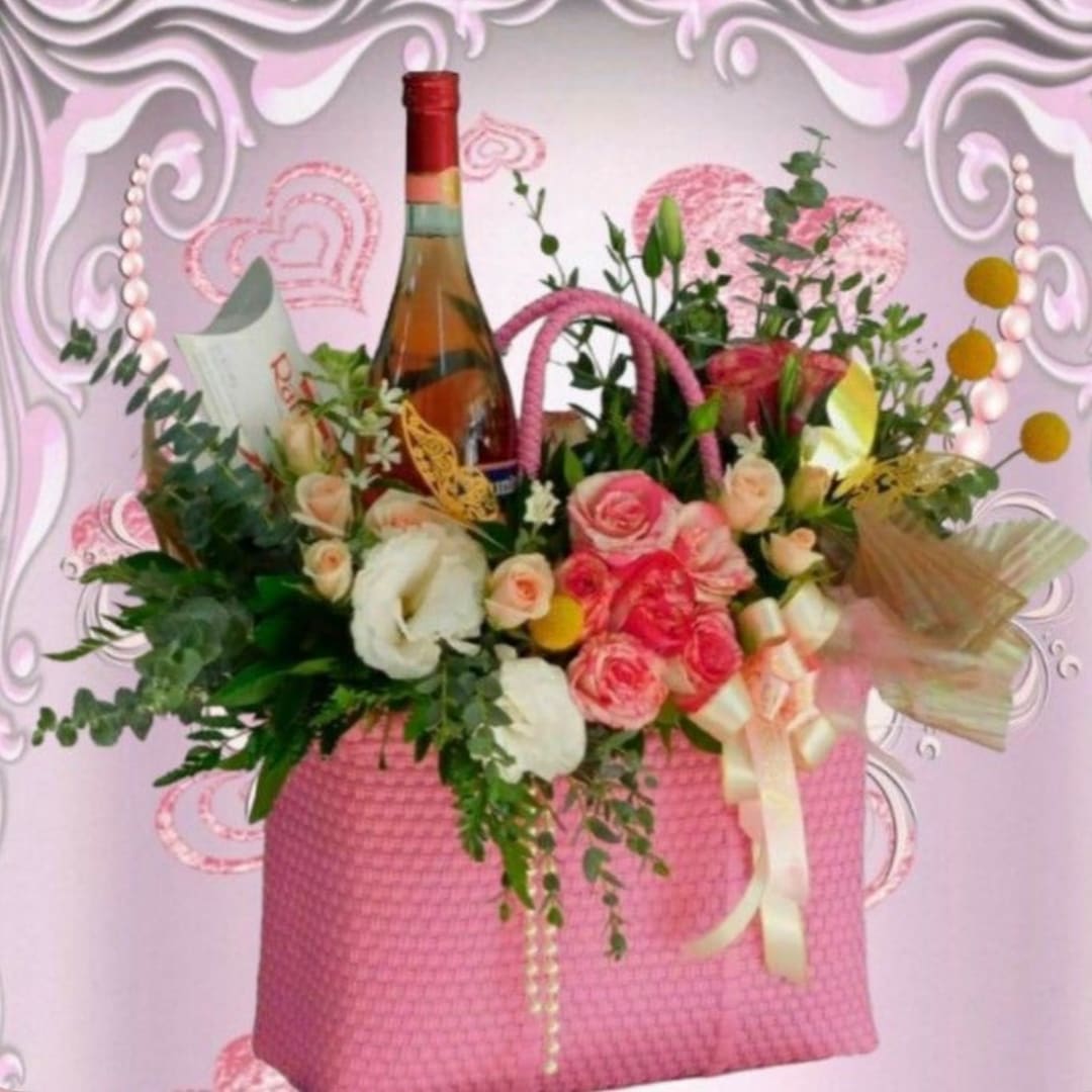 Pink gift basket with roses, white flowers, and a wine bottle