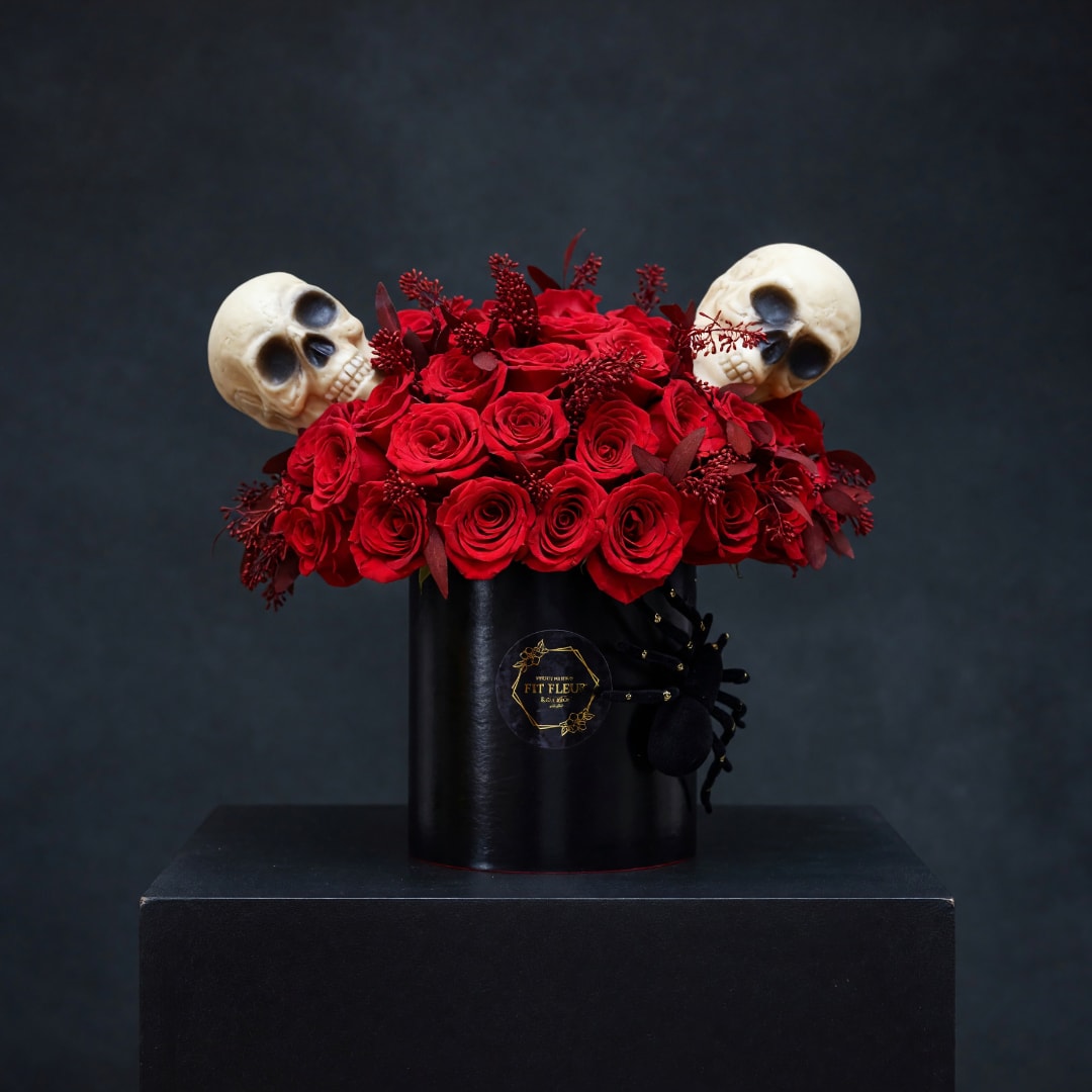 Red roses in a black hatbox with two skull decorations