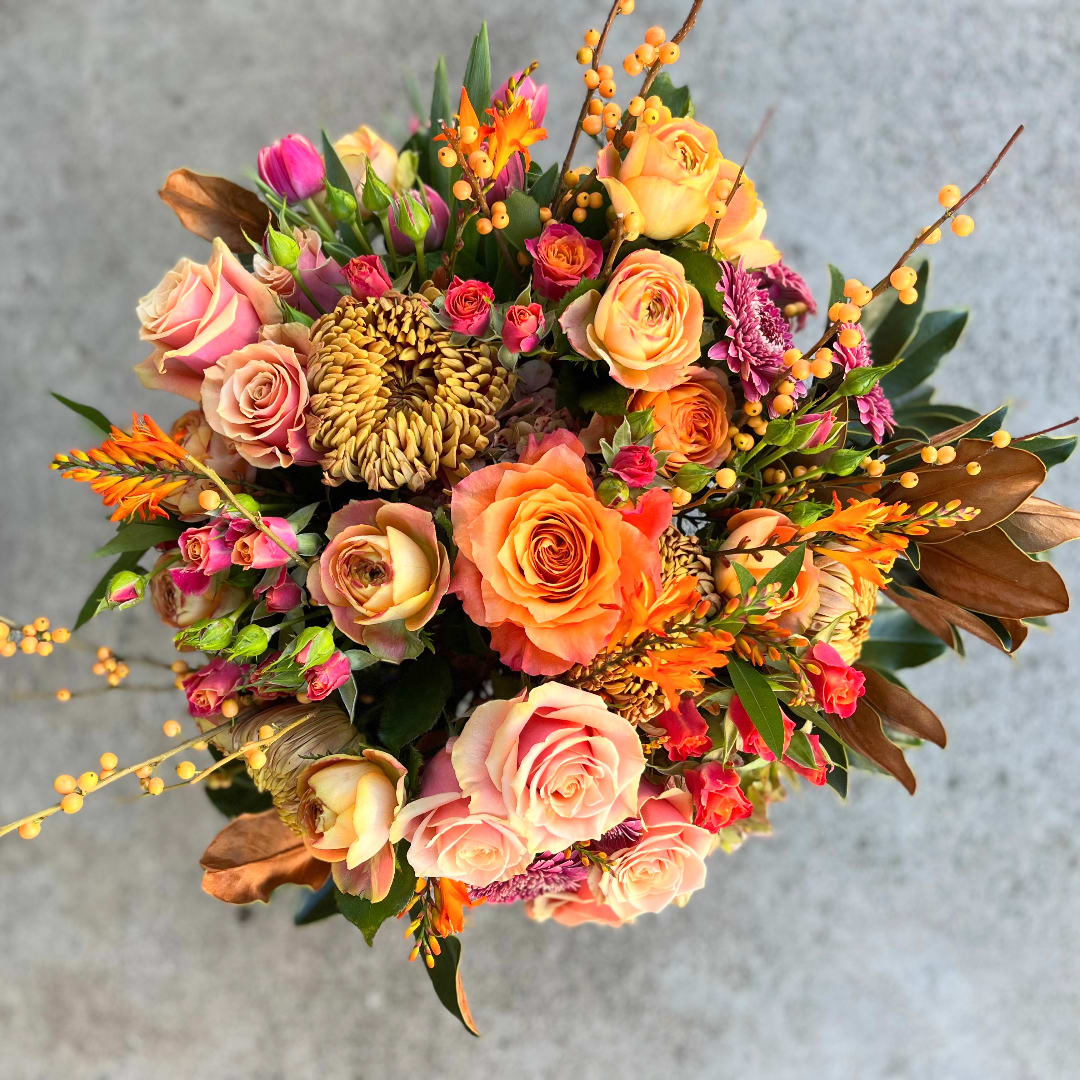 Mixed bouquet of peach and pink roses with orange accents
