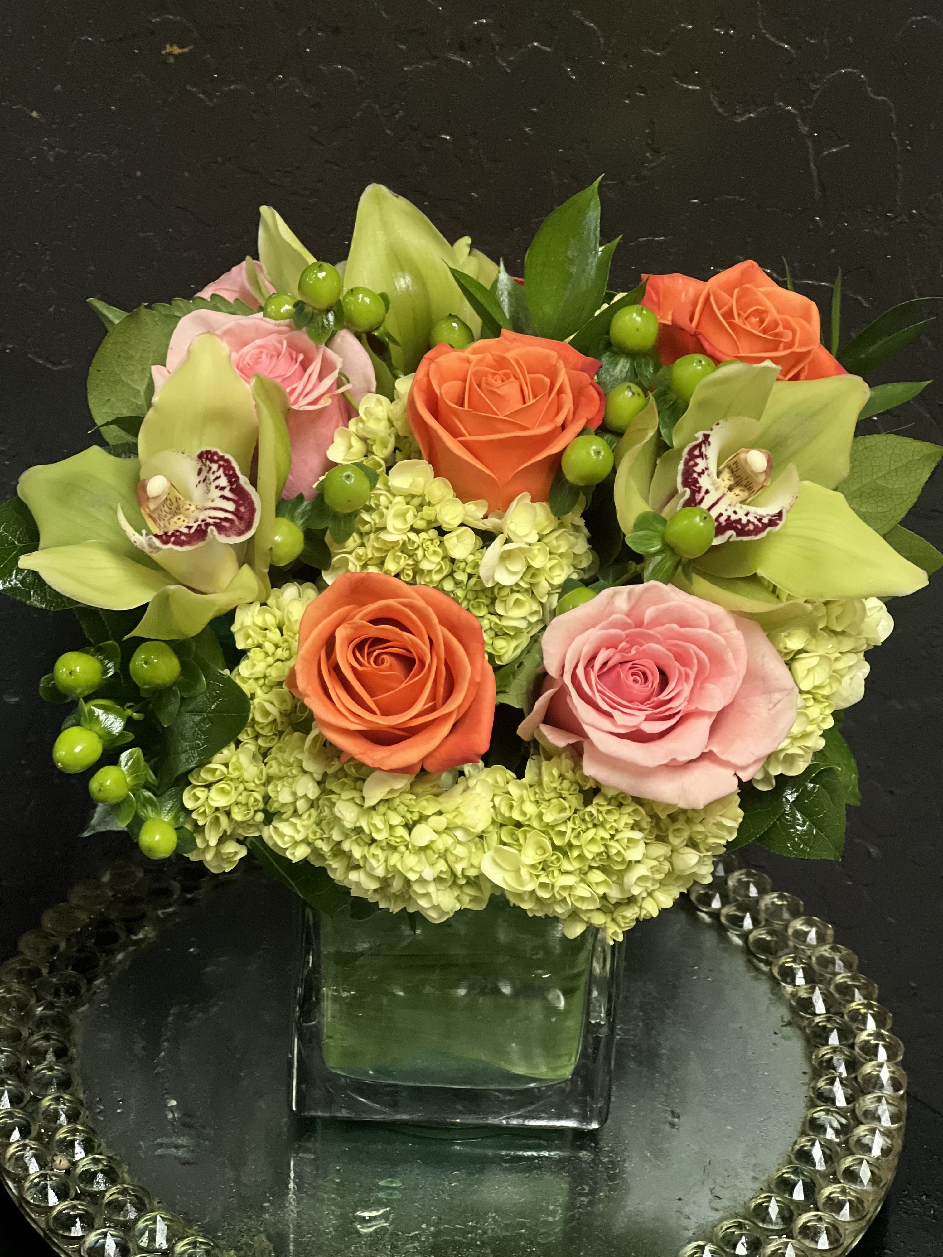 Mixed bouquet of roses, orchids, and hydrangeas in a glass vase