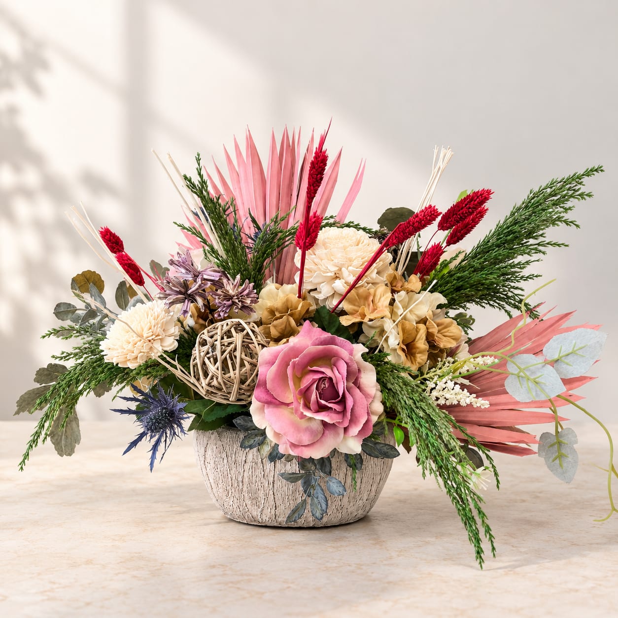 Pink and cream floral arrangement in a textured pot with dried accents