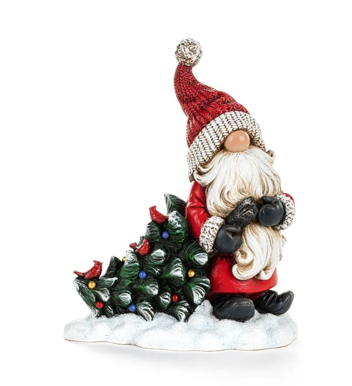 Santa figurine beside a small decorated Christmas tree on a snowy base