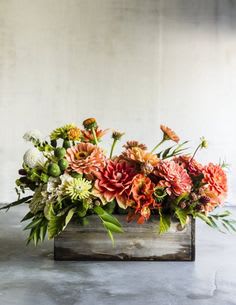 Low floral arrangement in a wooden box with orange and pink blooms