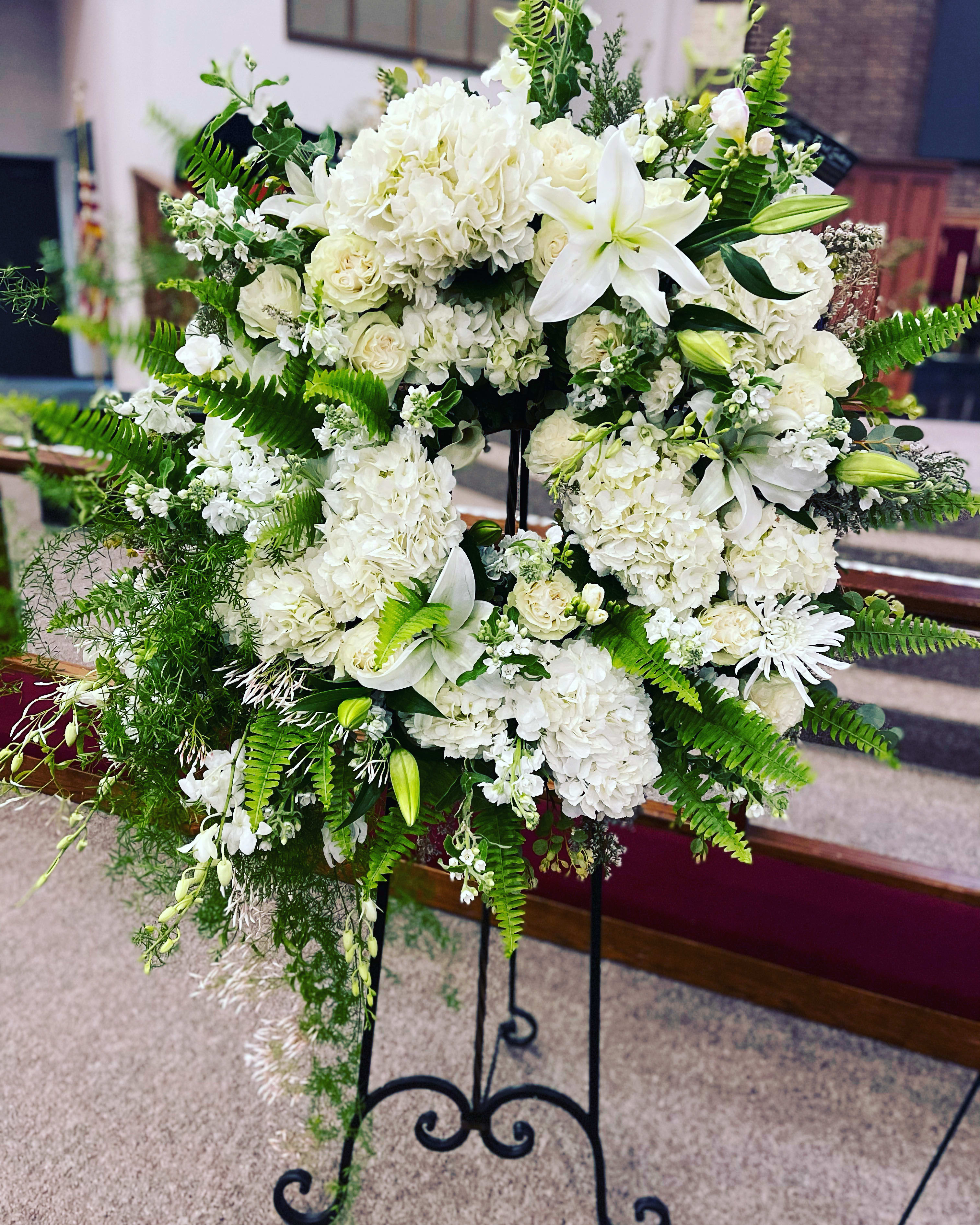 White floral standing spray with lilies, roses, and hydrangeas
