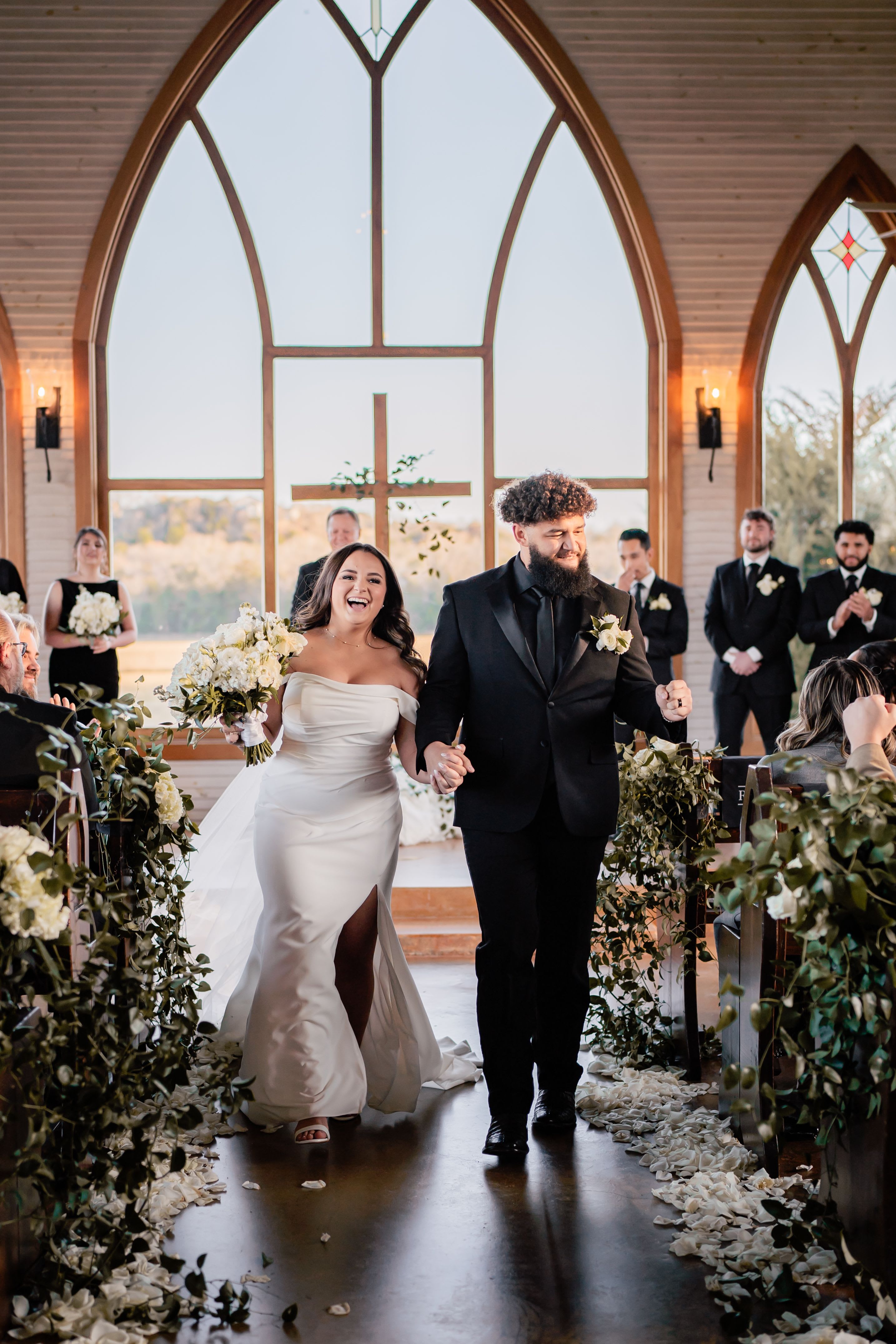 Bride and groom walking down the aisle with white floral arrangements