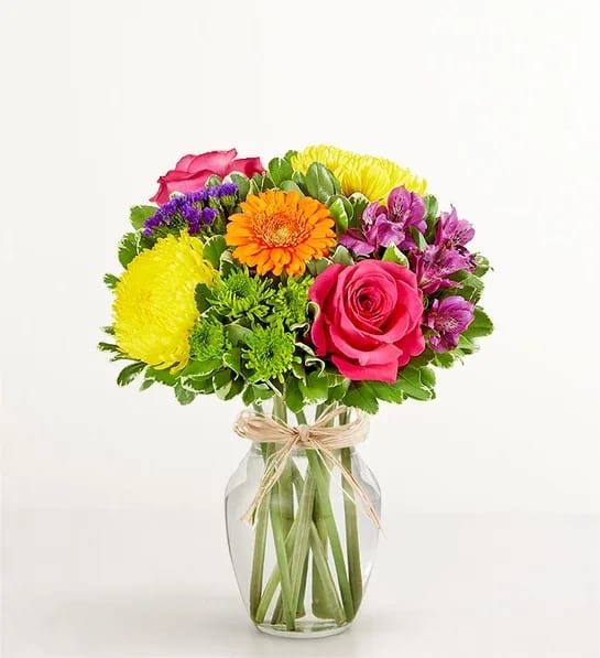 Mixed bouquet of bright flowers in a clear glass vase