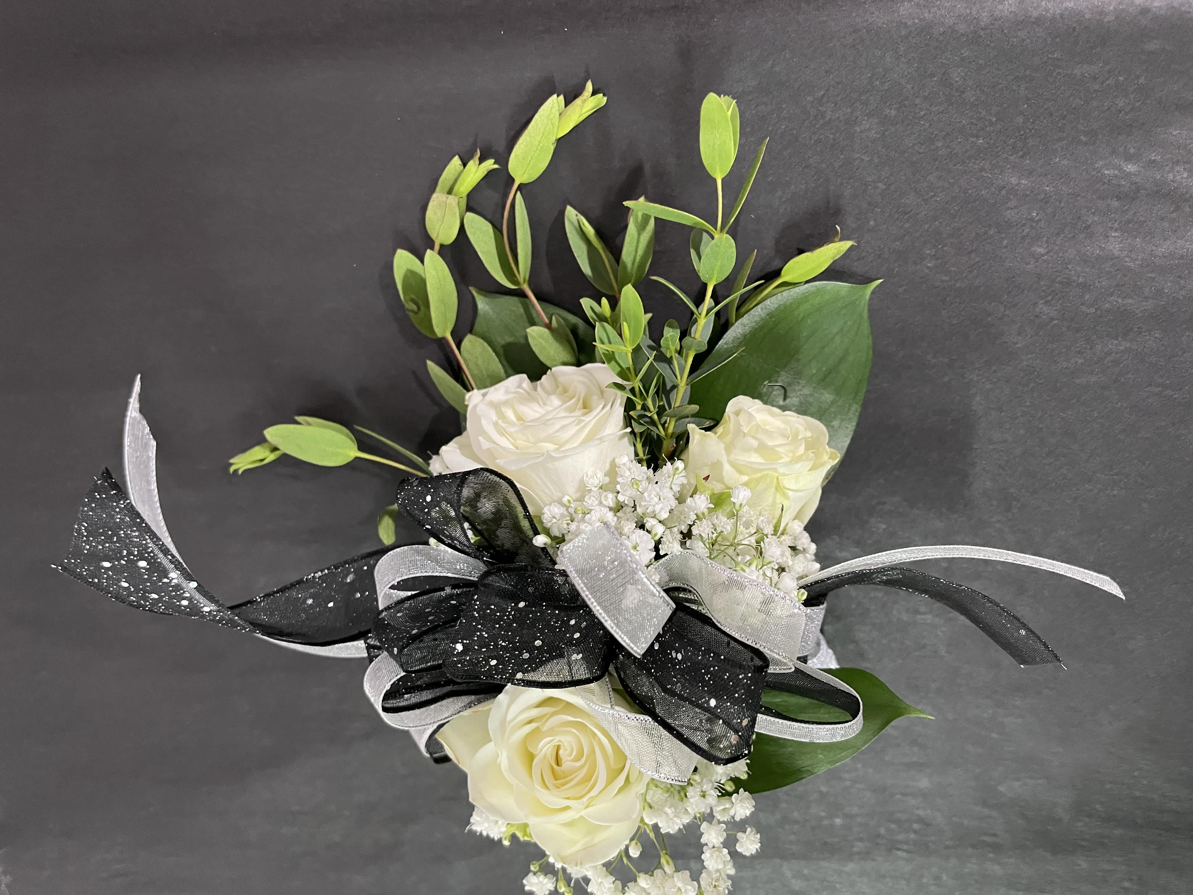 White rose bouquet with black and silver ribbon on a dark background