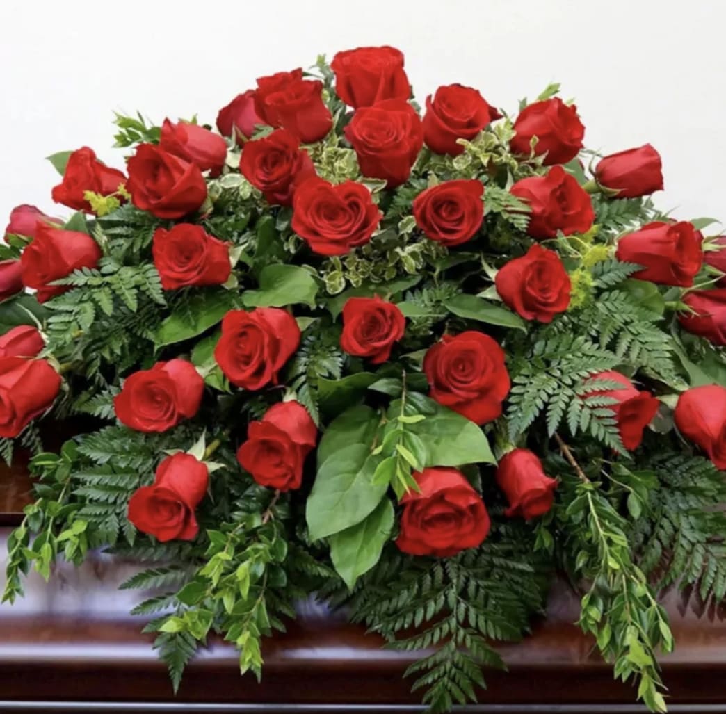 Large arrangement of red roses with greenery on a casket