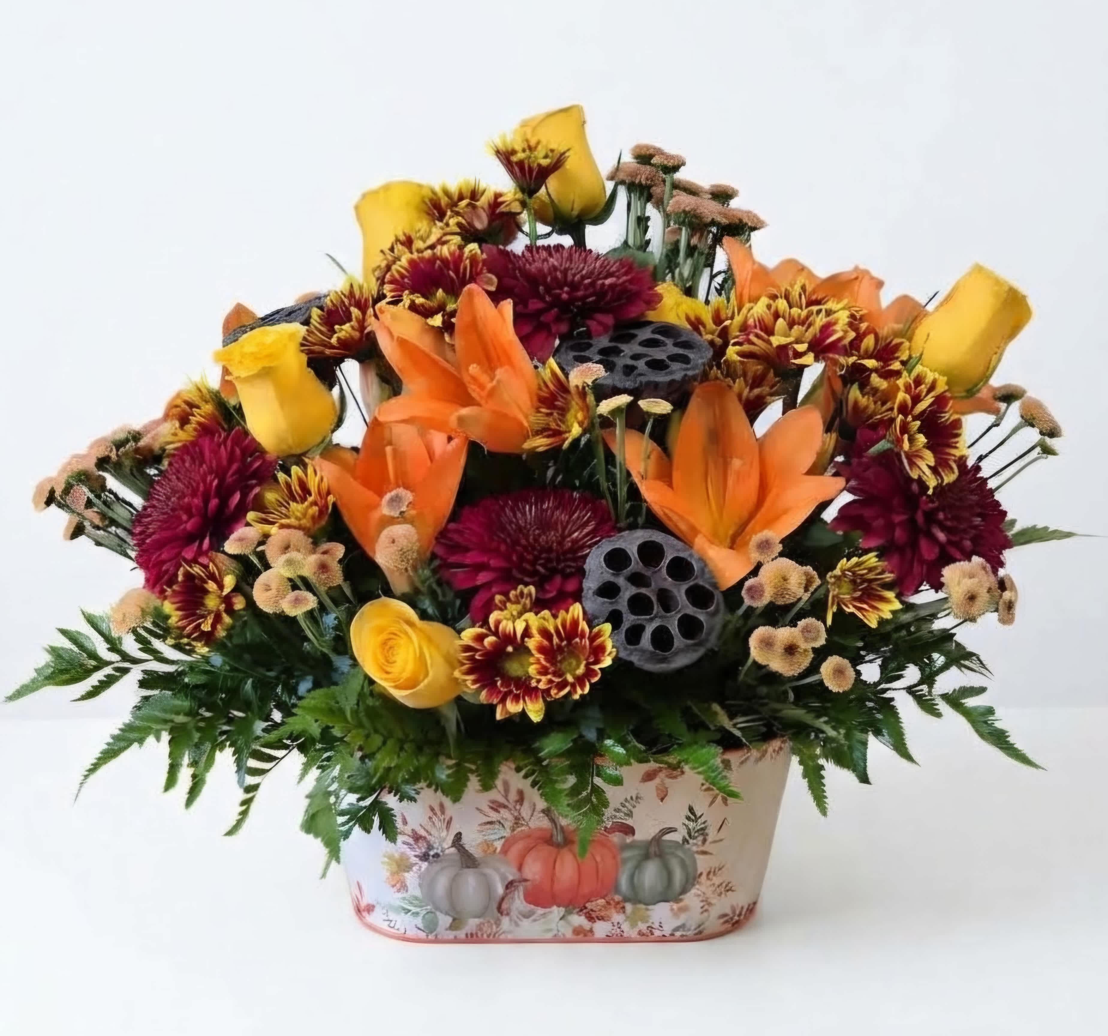 Autumn floral arrangement with orange lilies and yellow roses in a pumpkin-decorated container