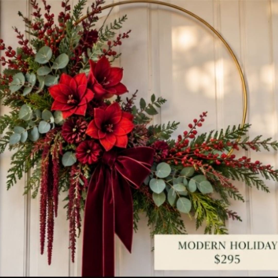 Holiday floral hoop arrangement with red blooms and a burgundy ribbon