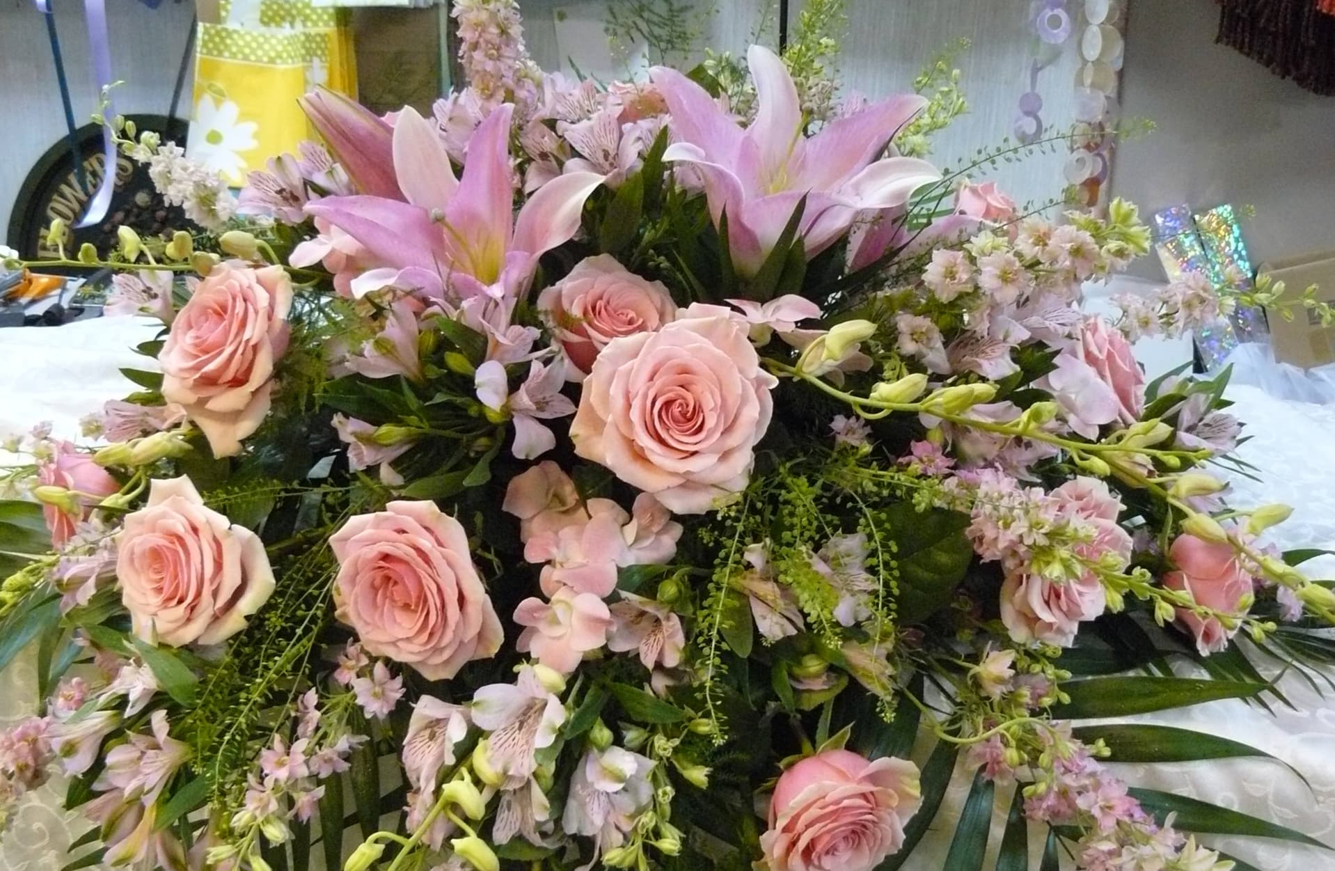 Pink Tone Half Casket  Cover - Casket Spray is a wonderful way to commemorate a life abundant in beauty and love.  Assorted  Pink Flowers,  Roses, Lilies, Orchids, Larkspur and assorted fancy greens. Designed &amp; Photographed in our Store. 