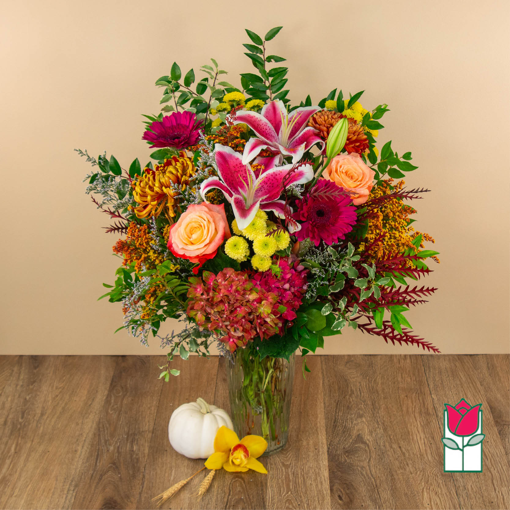 Mixed bouquet in a clear vase with pink lilies, roses, and mums