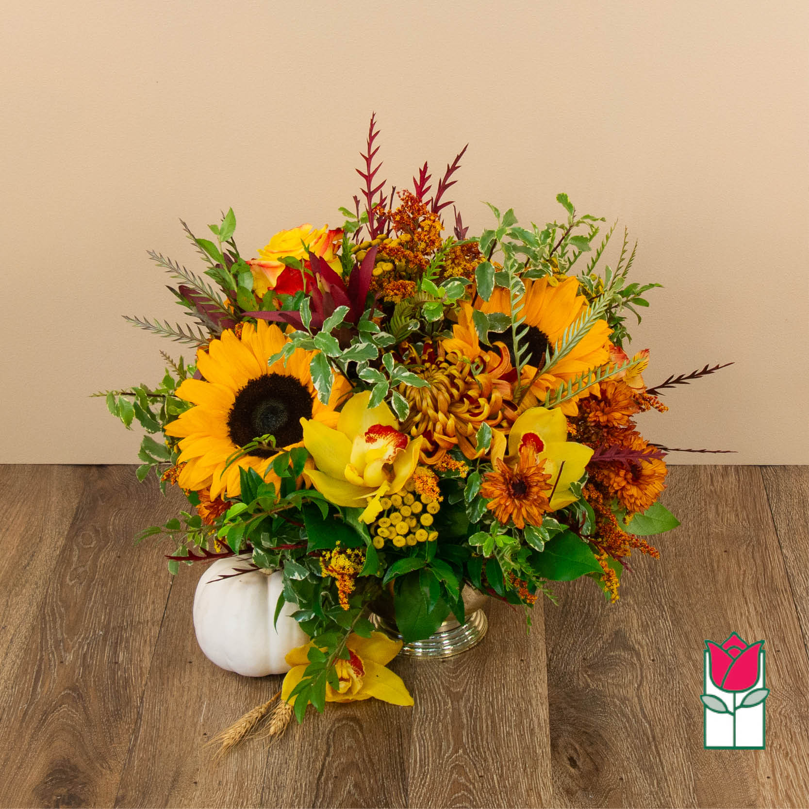 Autumn bouquet with sunflowers, orchids, and orange blooms in a silver vase